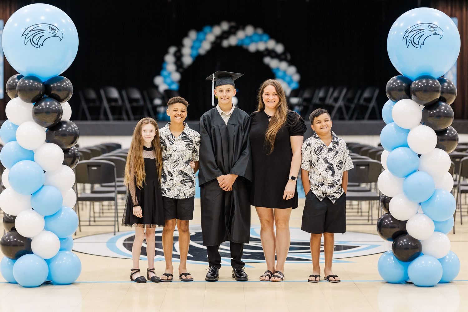 Graduation ceremony setup with blue and white balloon arrangements and seated guests.