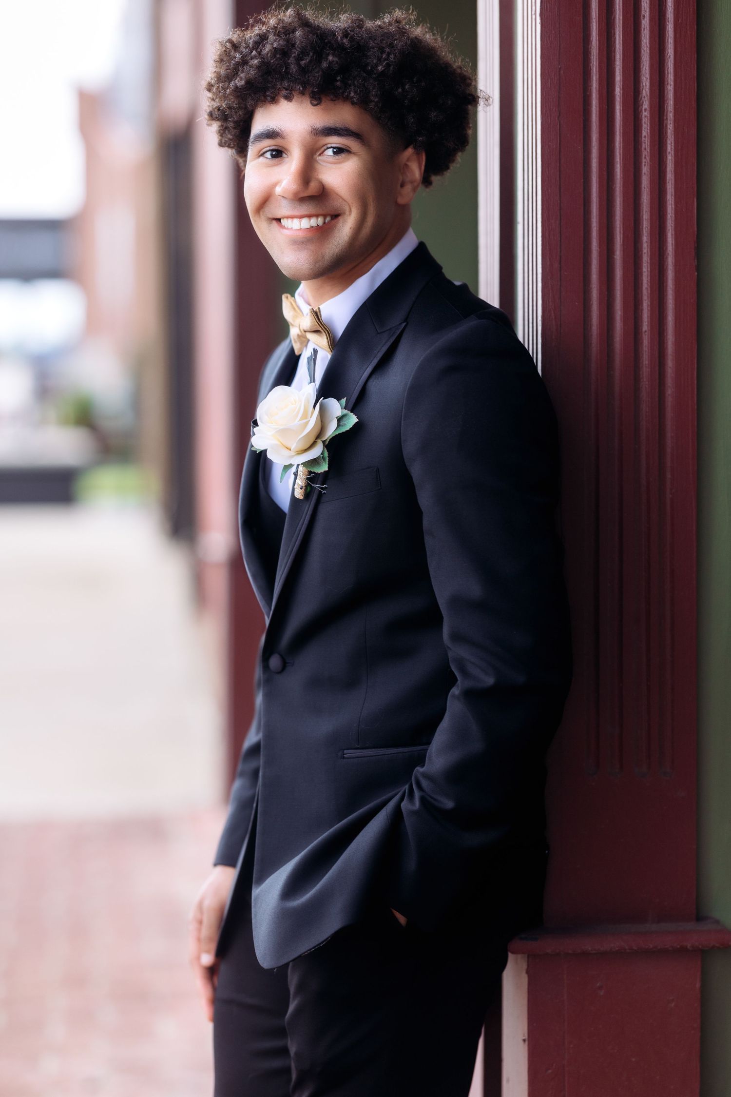 Classic black tuxedo portrait session against burgundy architectural columns.