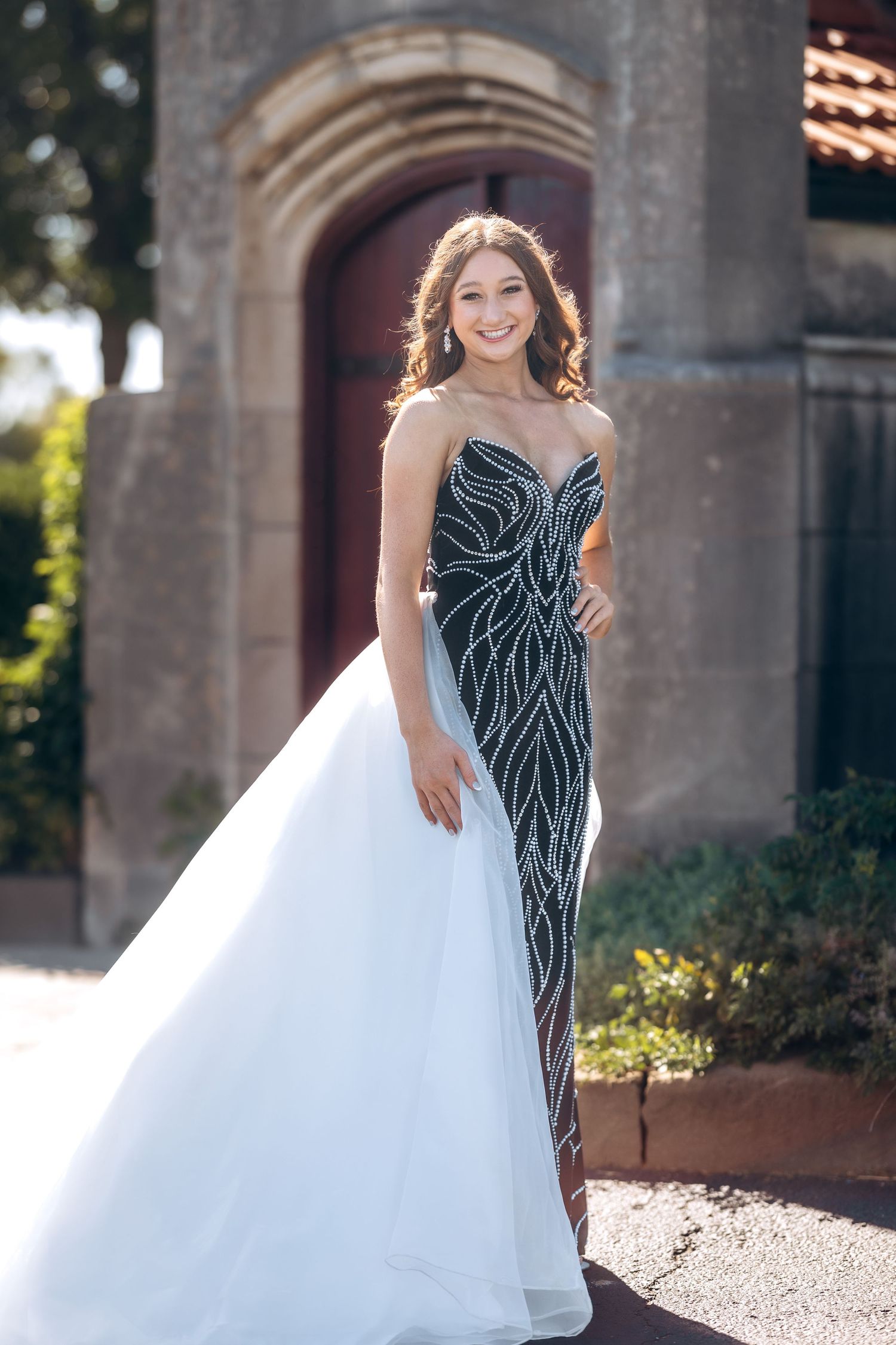 A fitted black gown with white overlay captured in an elegant outdoor setting.