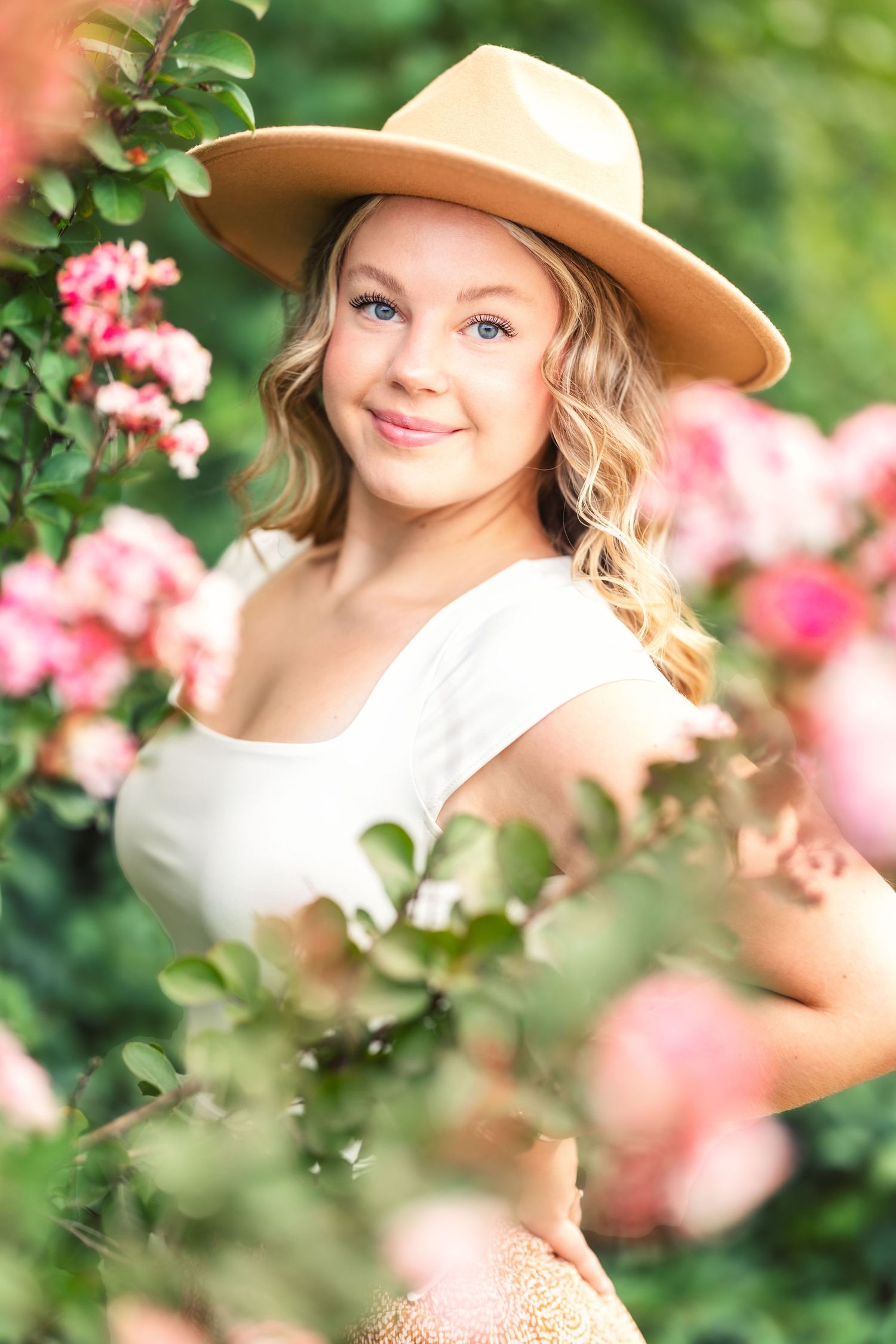 Dreamy garden portraits with pink roses and tan wide-brimmed hat.