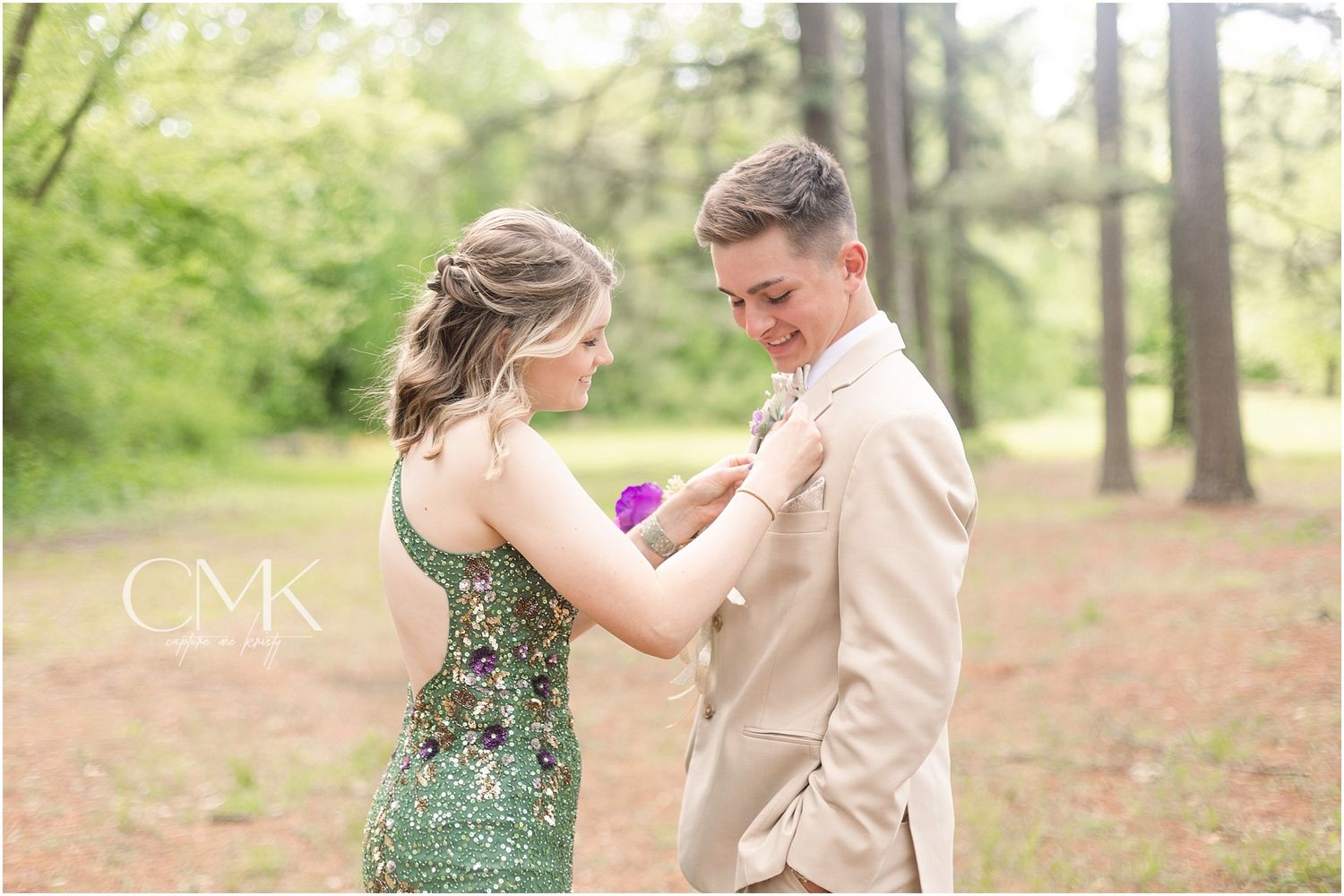 A candid moment between two people during prom preparations in an outdoor forest setting.