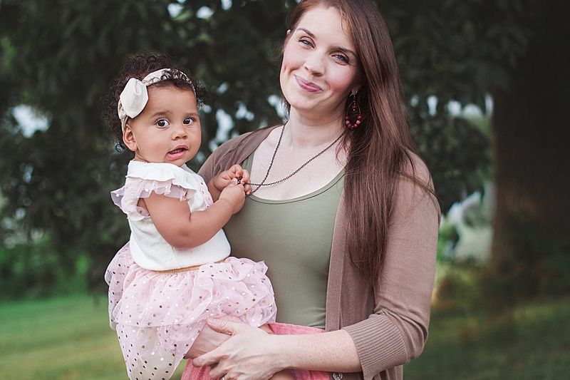 Portrait of parent and child in coordinating outfits posed together outdoors.