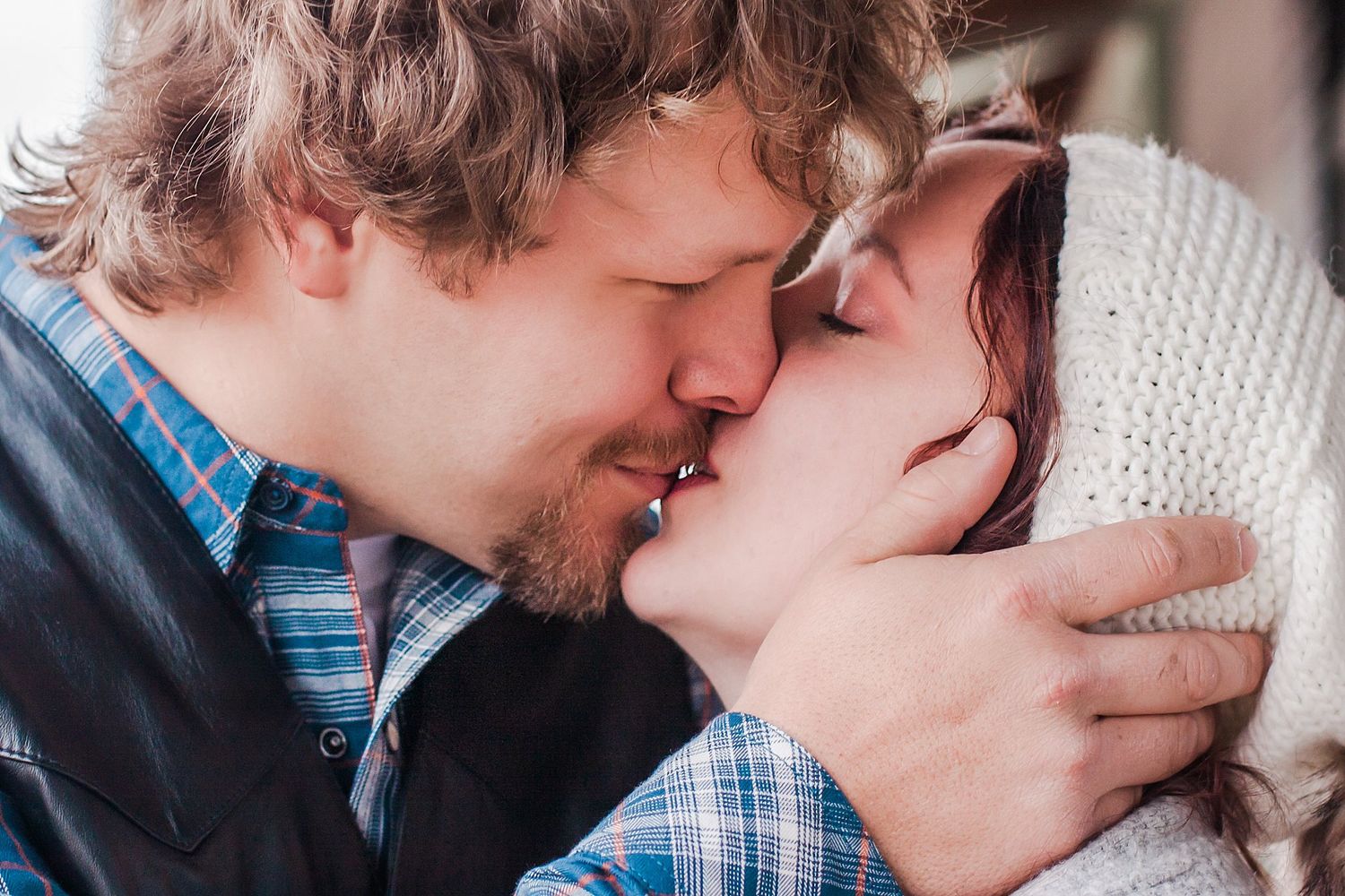 man kisses woman while gently holding the side of her head