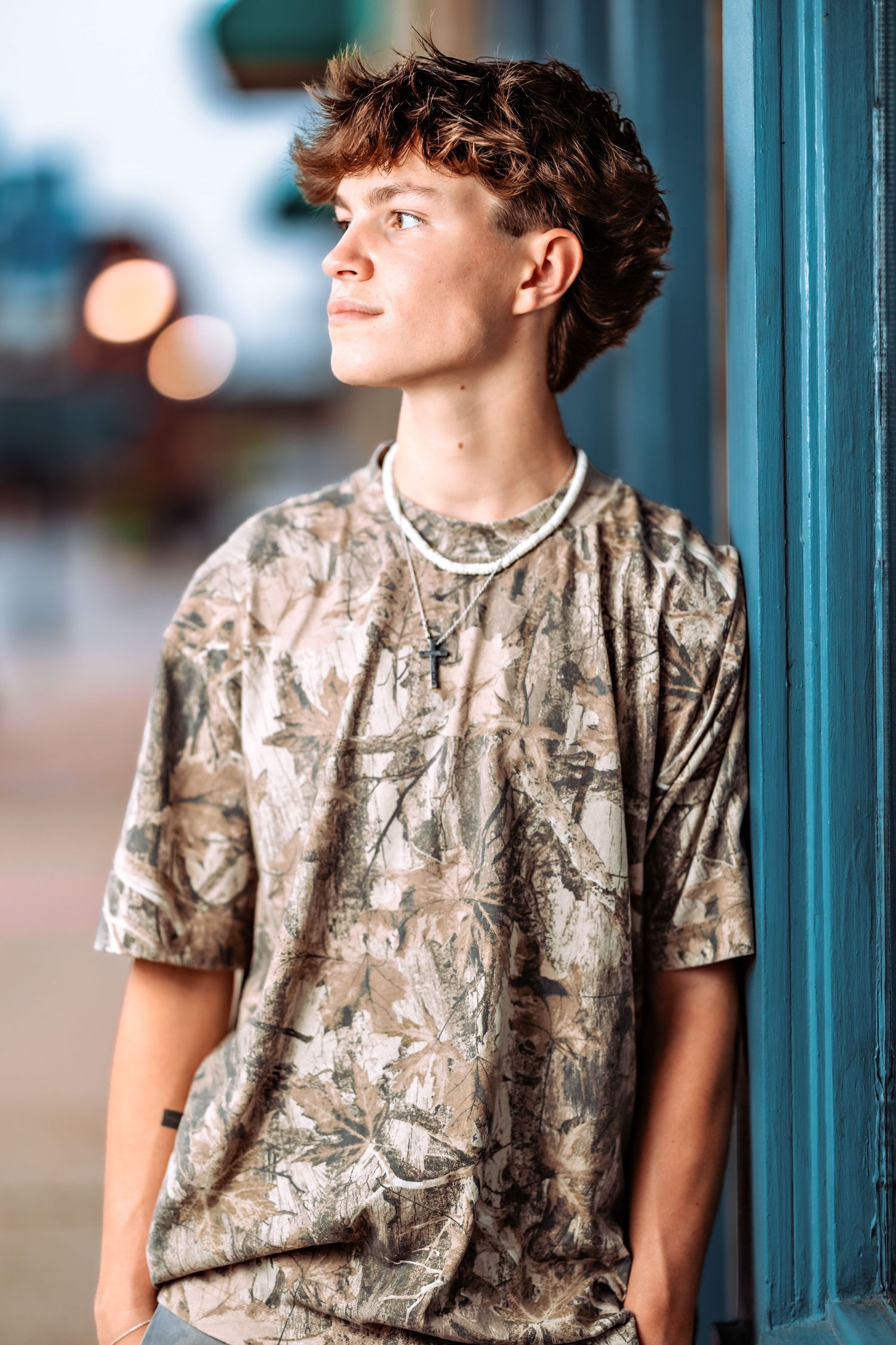 Person wearing a camouflage pattern t-shirt poses against a blue-tinted background.