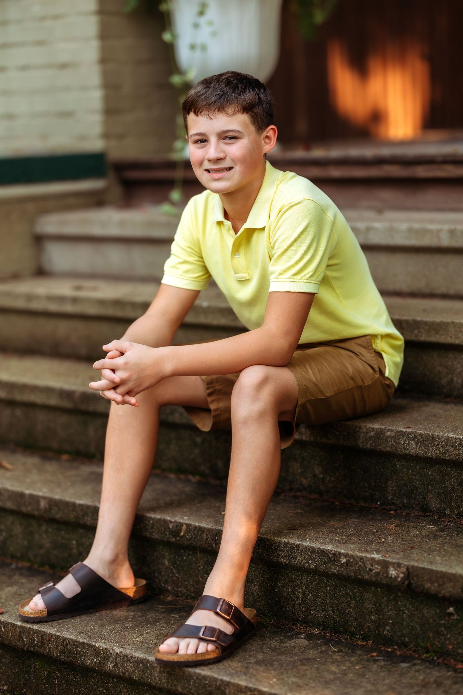 Person in yellow shirt sits on concrete steps during an outdoor photo session.