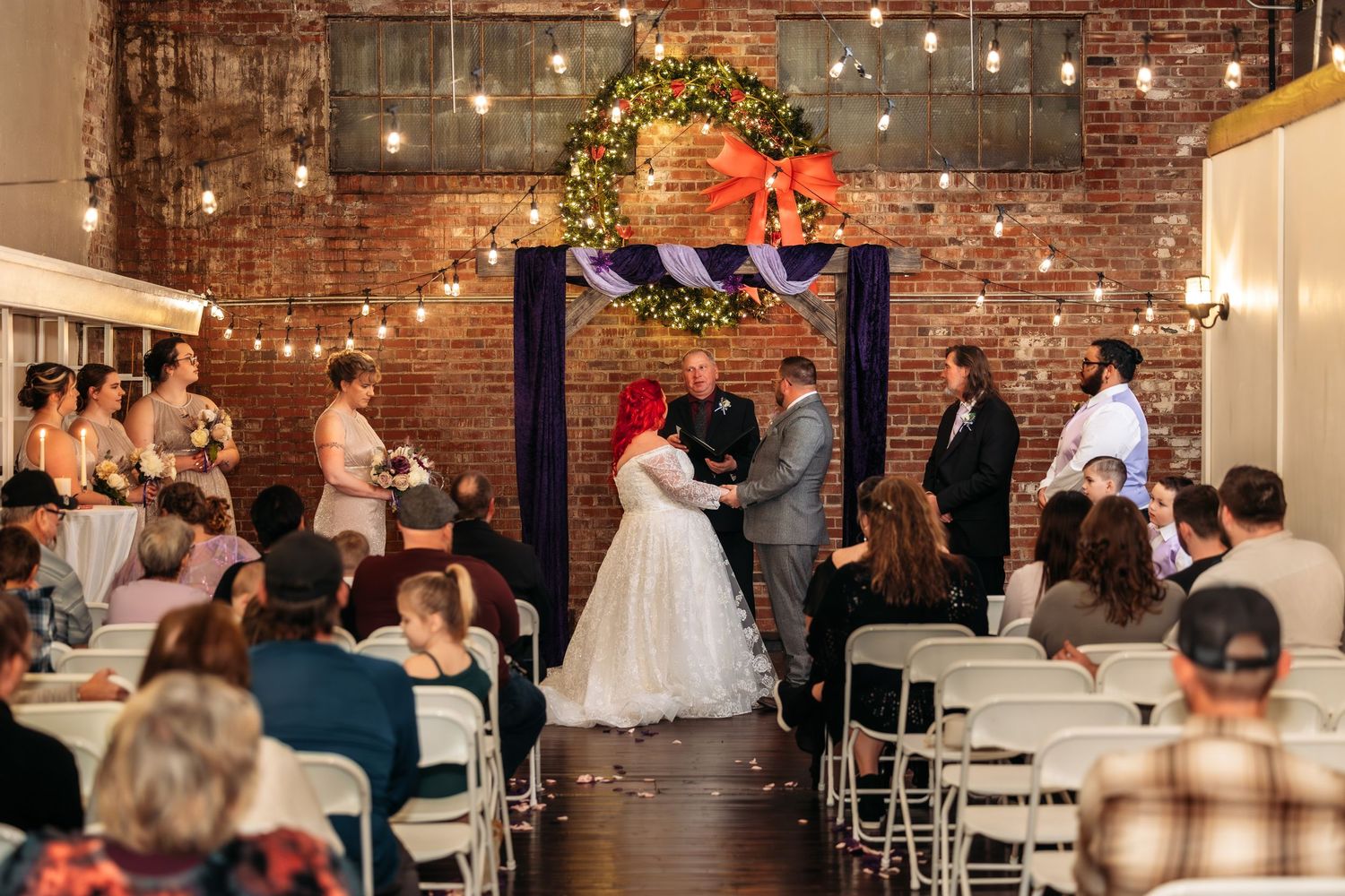 Wedding reception venue with exposed brick walls, string lights, and rustic decor.
