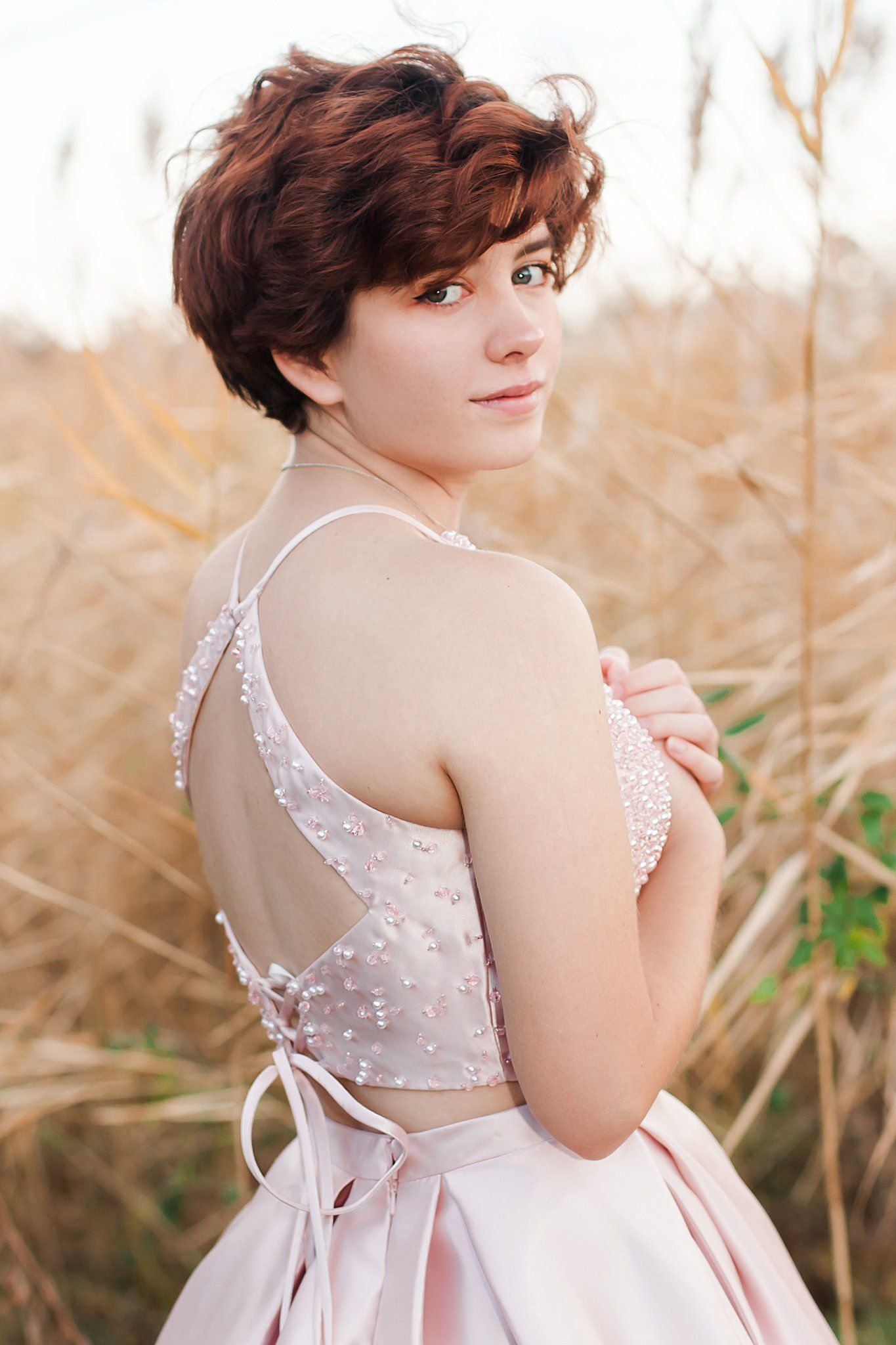 Back view of beaded dress with corset detail against natural backdrop.