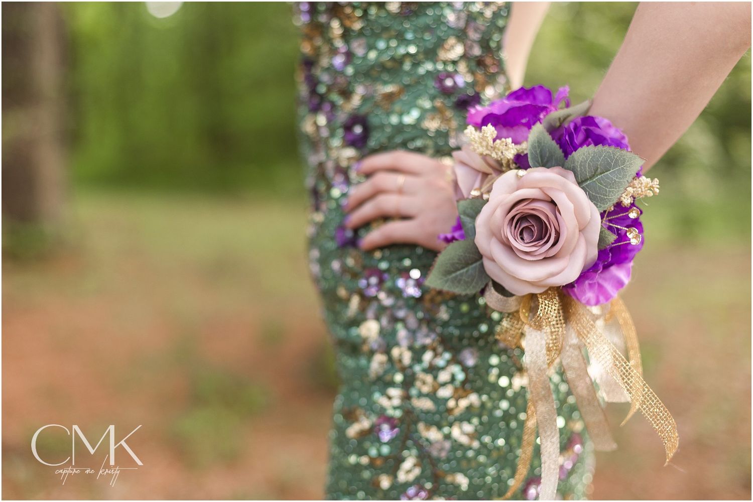 Close-up of a purple and pink floral wrist corsage against a sparkly green formal dress.