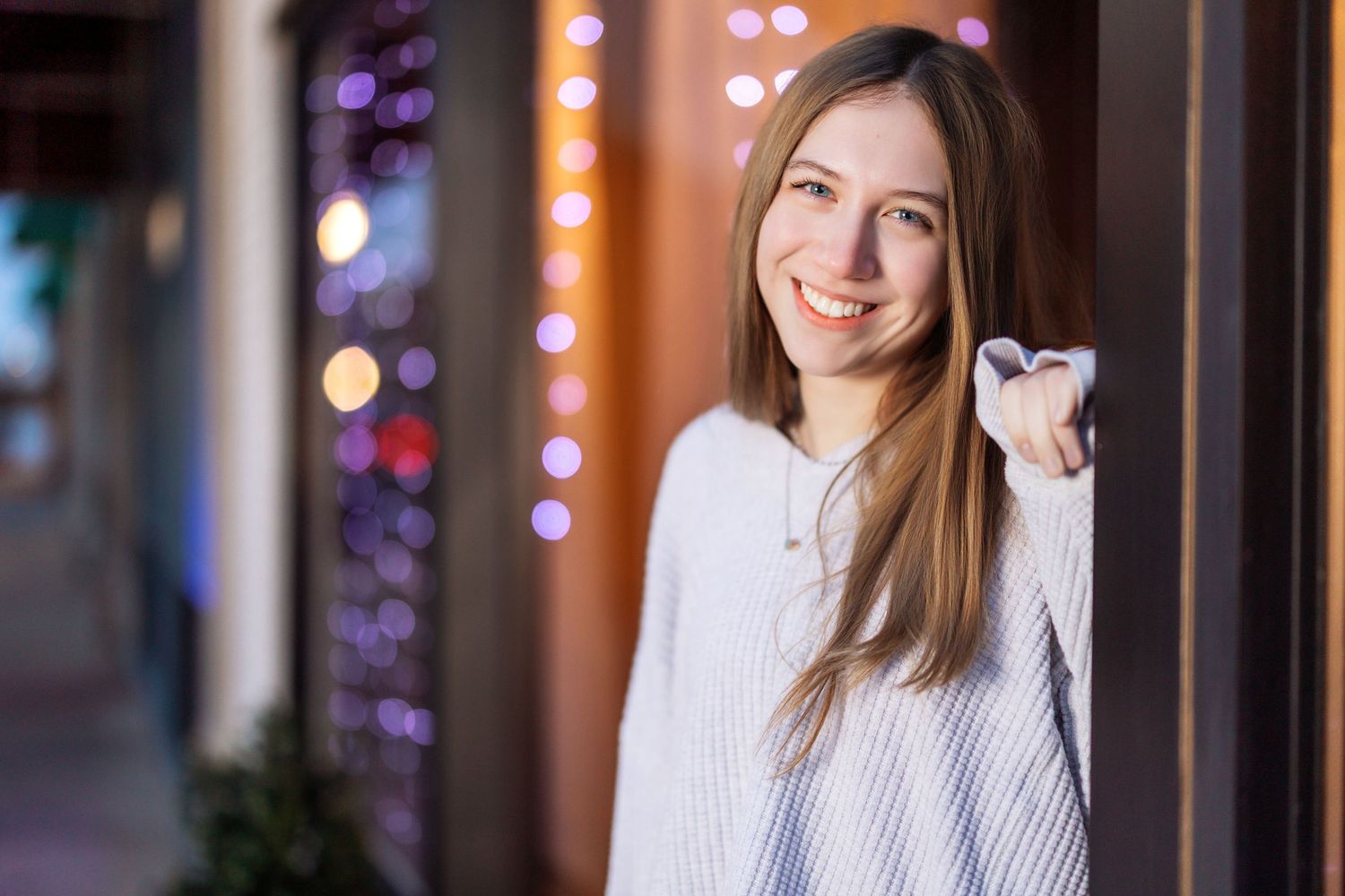 Person in white sweater photographed against evening city lights.