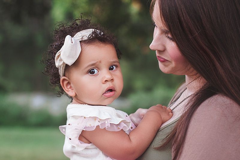Intimate side profile portrait of parent and child in natural outdoor setting.