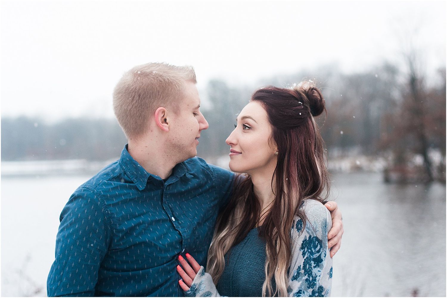 A couple in coordinating blue outfits shares a tender moment during their winter photoshoot.