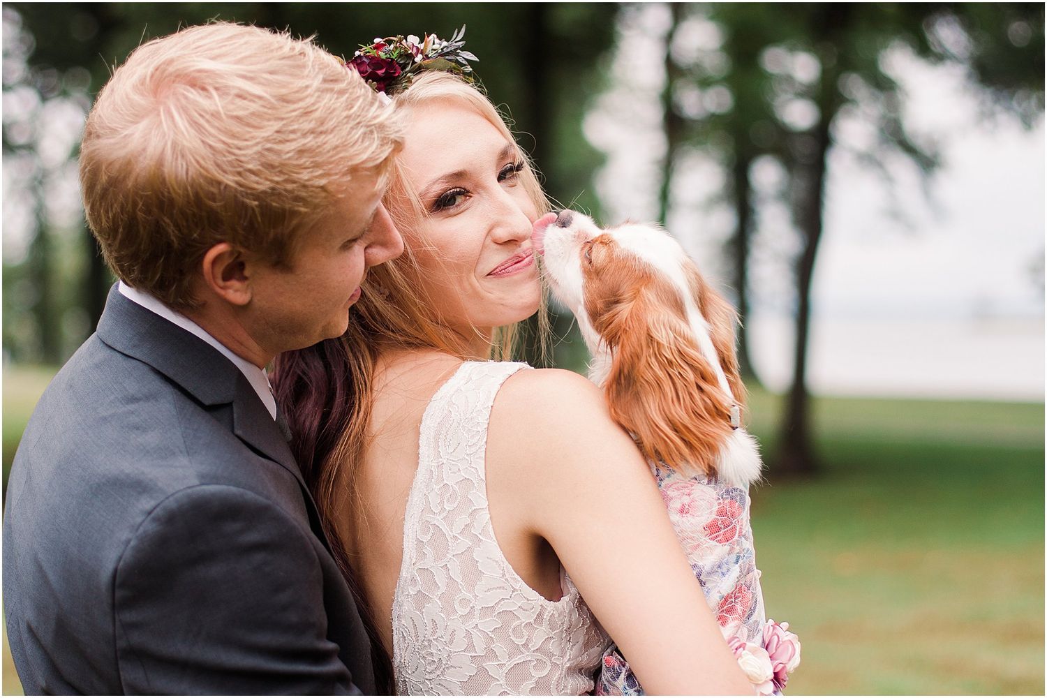 A couple shares an intimate moment with their dog during their outdoor wedding portraits.