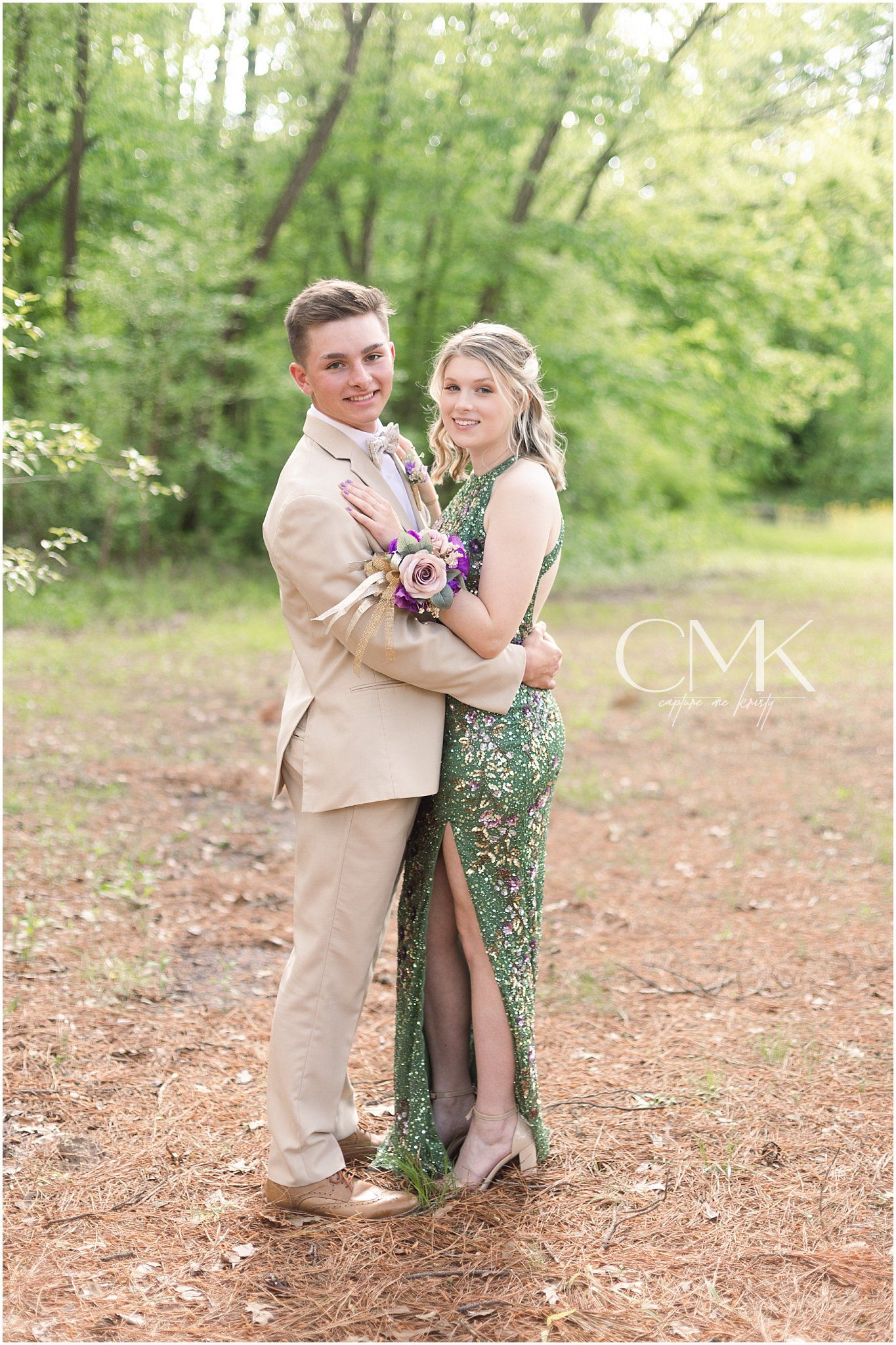 A loving embrace between a formally dressed couple on a forest path with spring greenery.