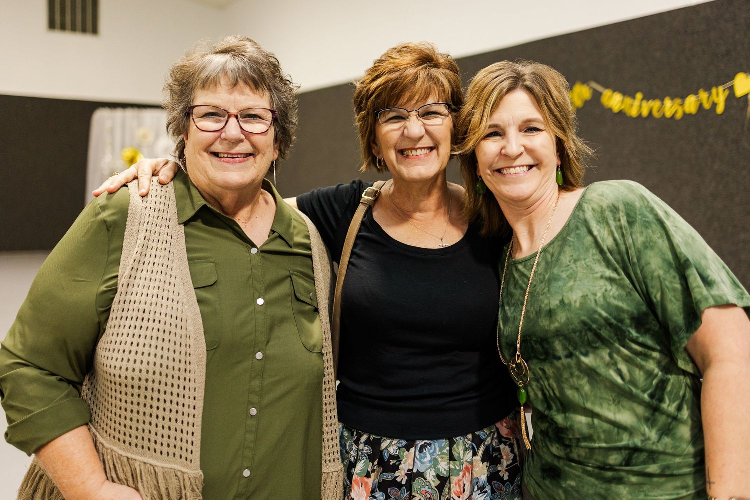 Group of attendees in casual green and tan outfits gathered at an indoor event.