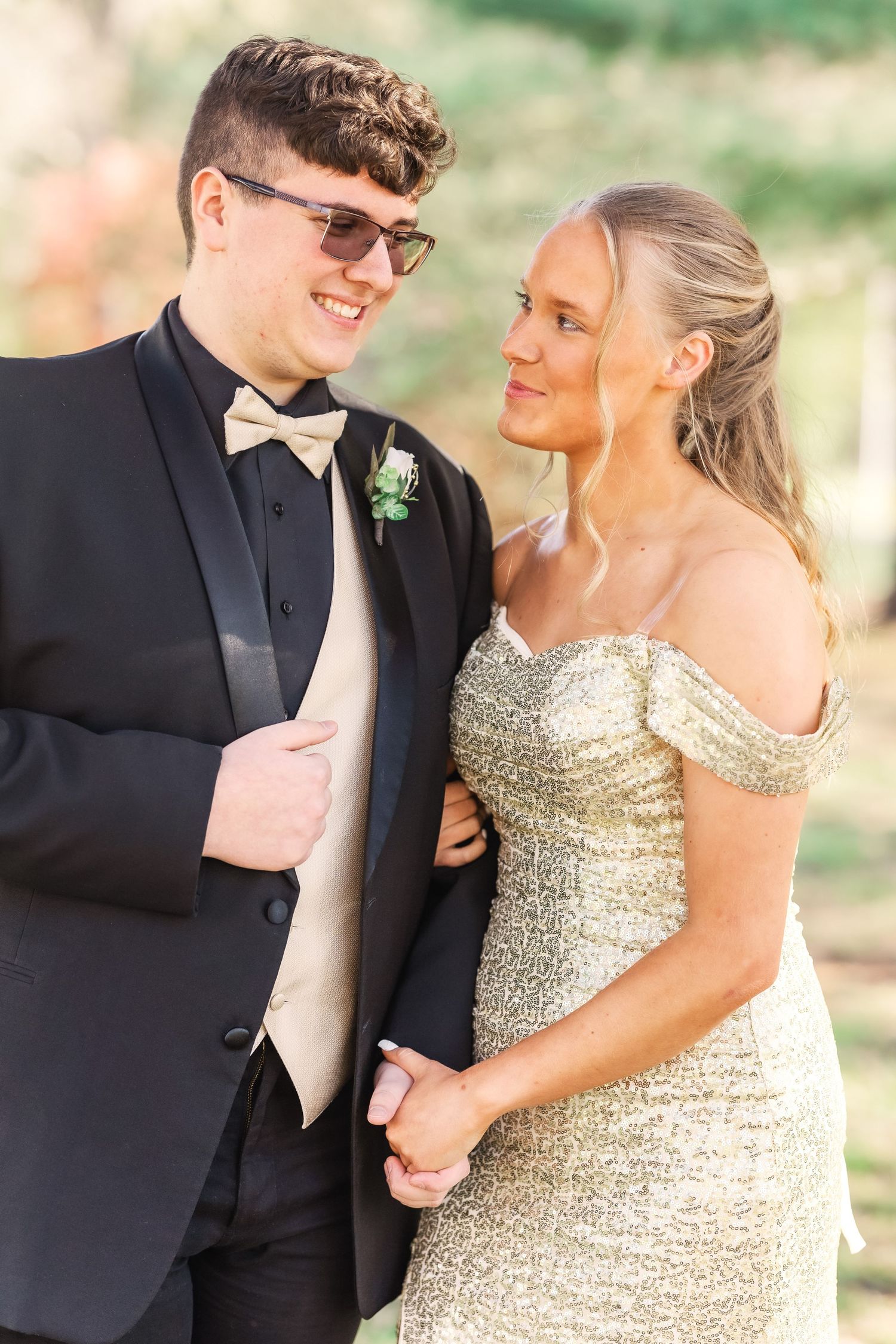 Couple in formal wear posing together under blooming spring trees.