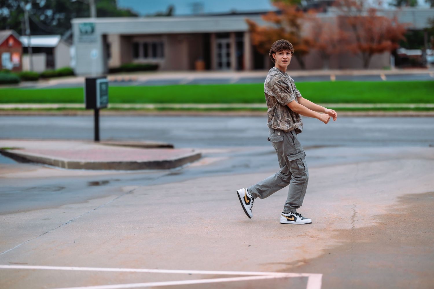 A skateboarder performs a sequence of tricks on a concrete path through an urban park area.