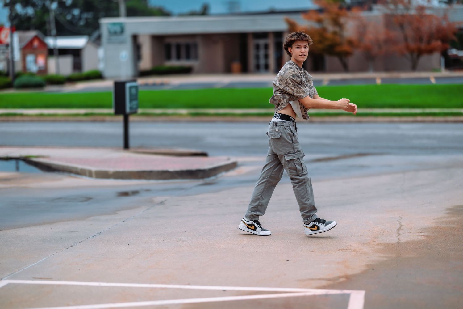 A person wearing casual clothes skates at an outdoor skate park on a cloudy day.