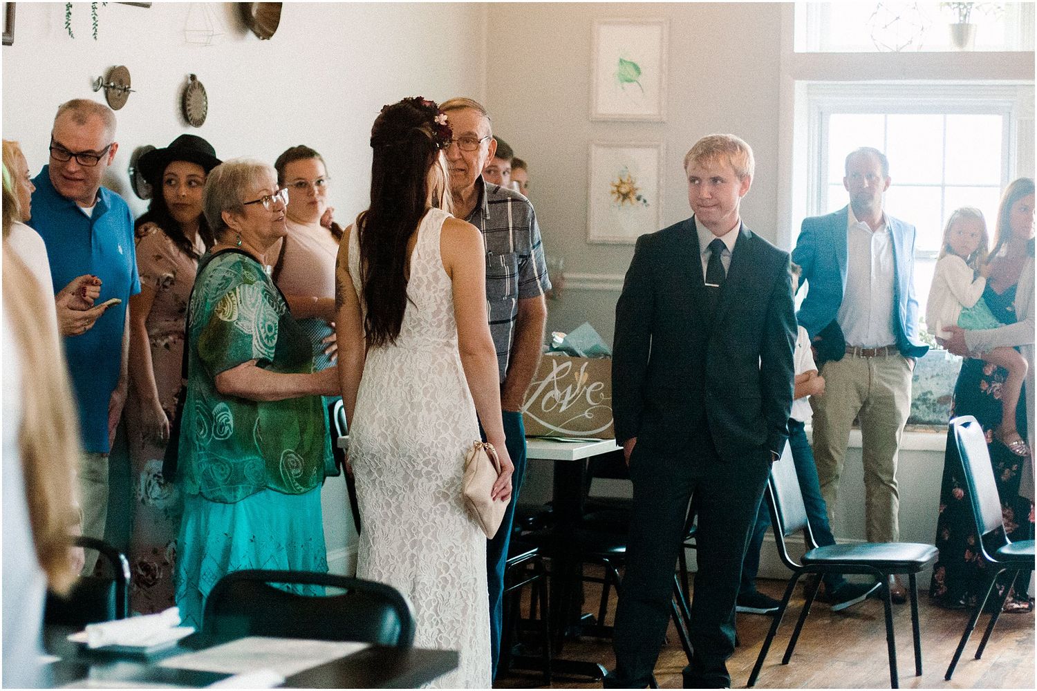 Wedding guests gather in a bright indoor venue during a ceremony.