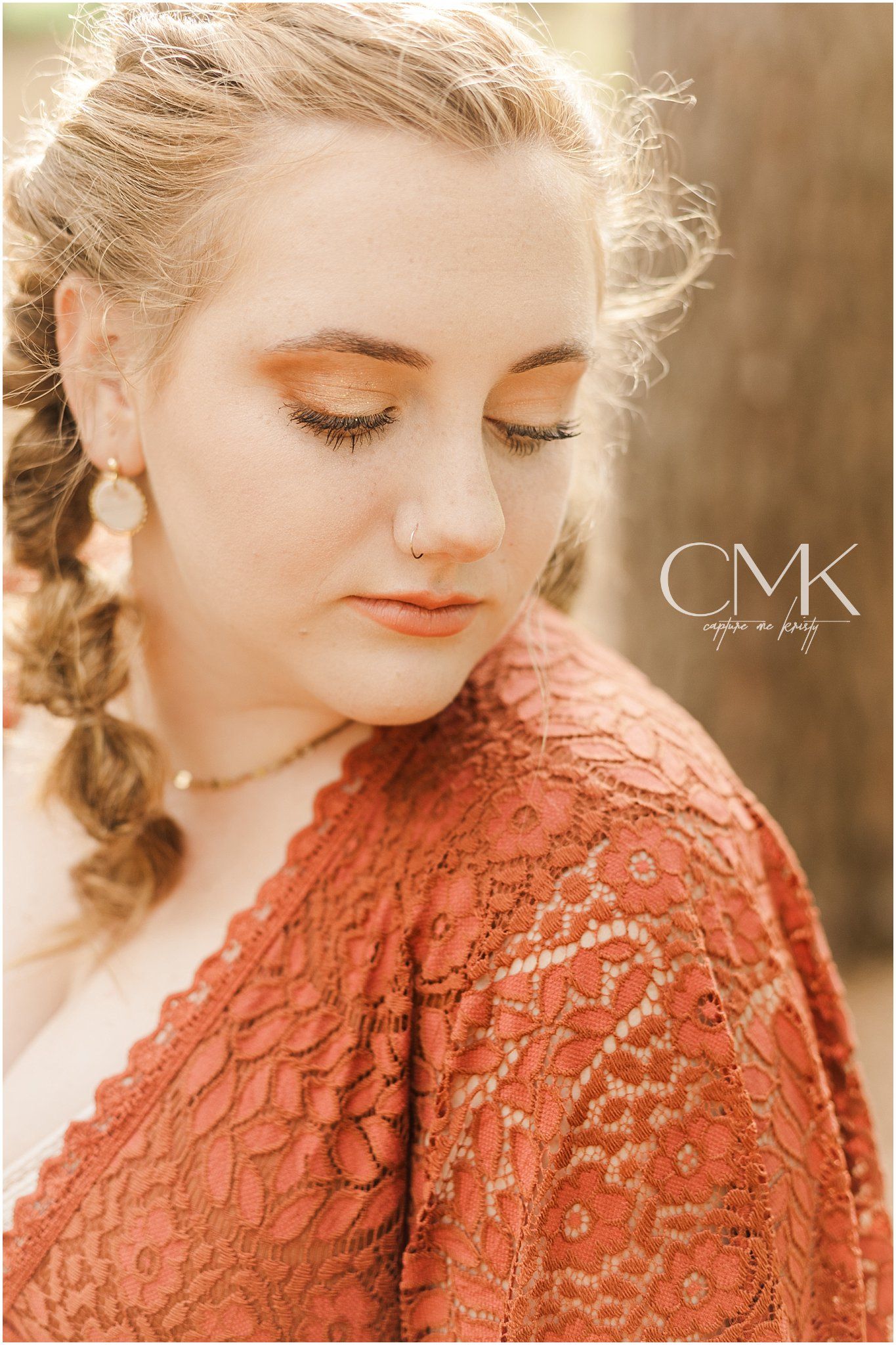 Close-up portrait showing delicate makeup and lace details against a soft forest backdrop.