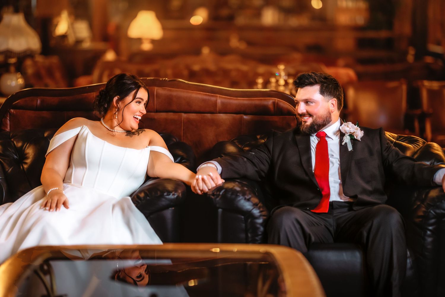 Couple in formal wedding attire dancing together on a wooden floor in warm lighting at their reception.