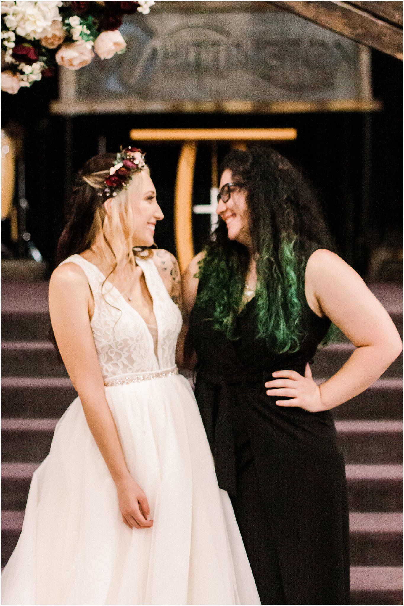 Two people share a candid moment at a rustic wedding venue with floral decorations.