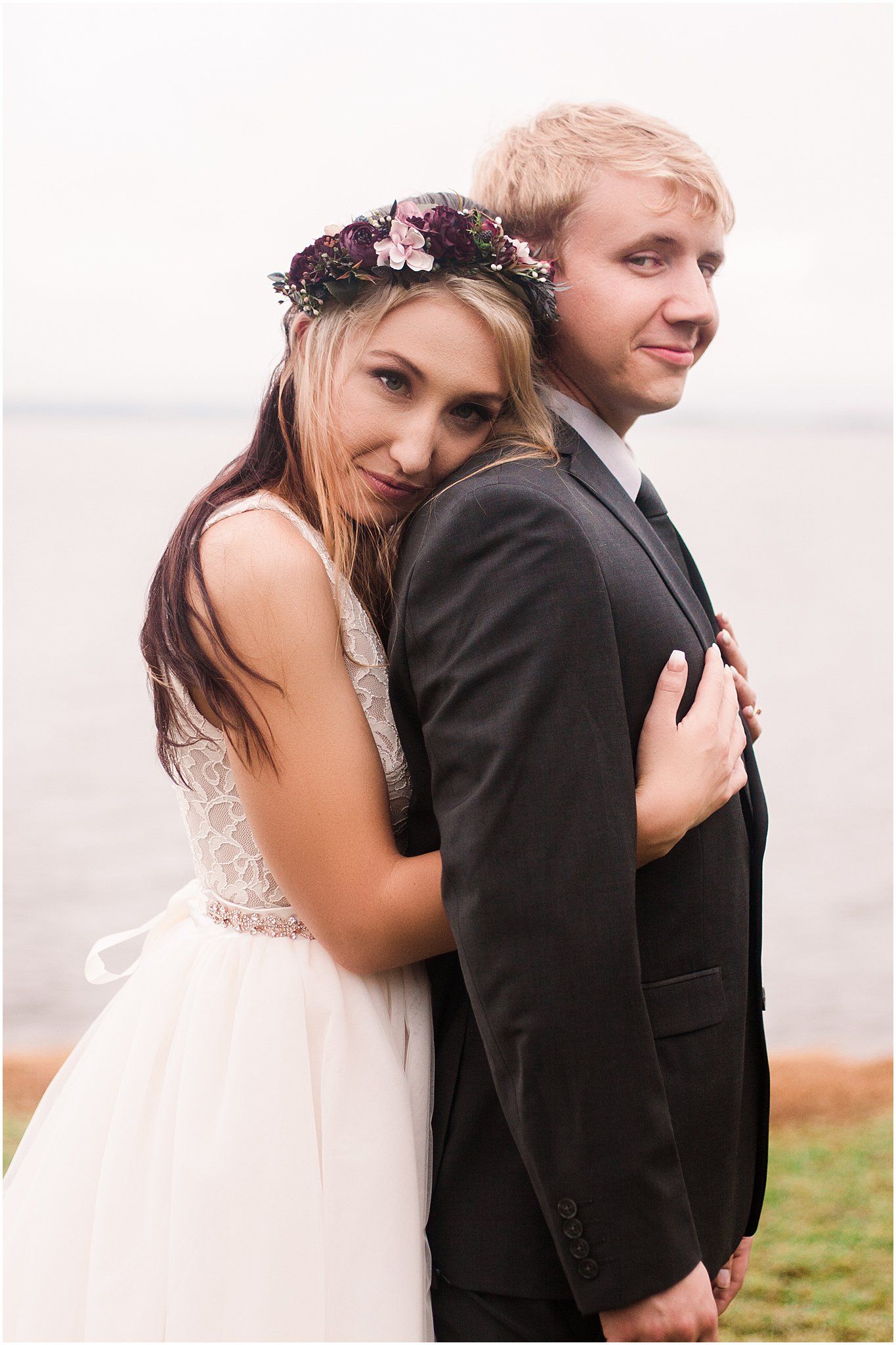 Romantic embrace between newlyweds with a waterfront backdrop during their wedding photoshoot.