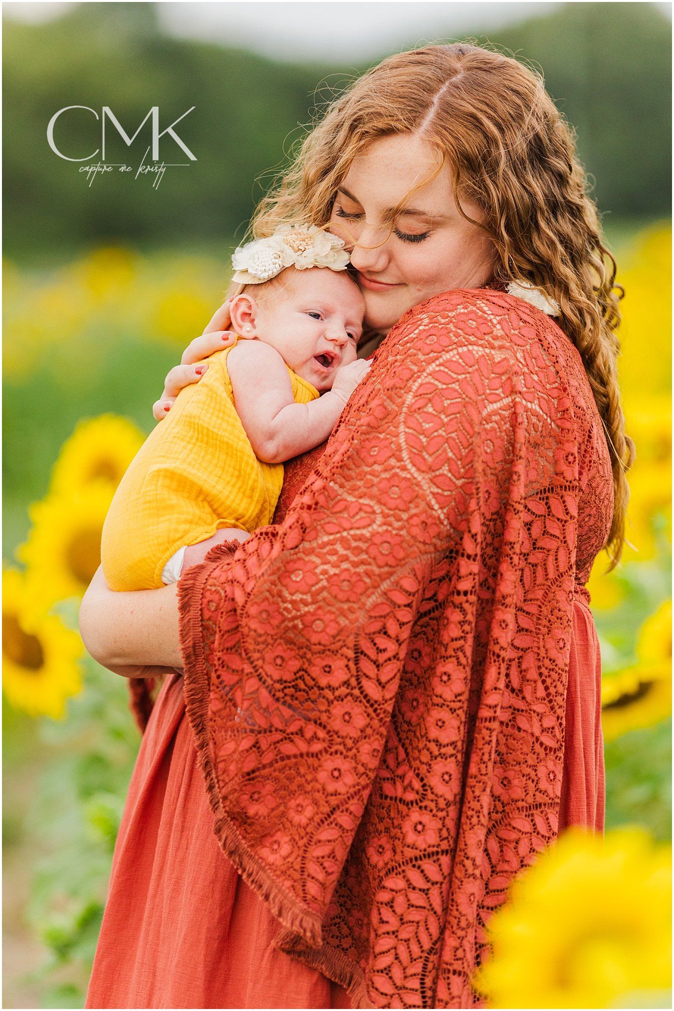 Tender moment between mother and baby captured in sunflower garden setting.