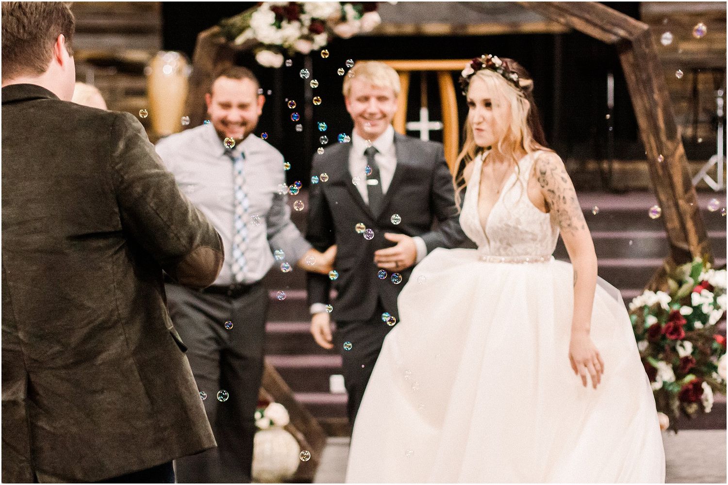 Joyful reception moment with guests celebrating under rustic wooden decor and floral arrangements.