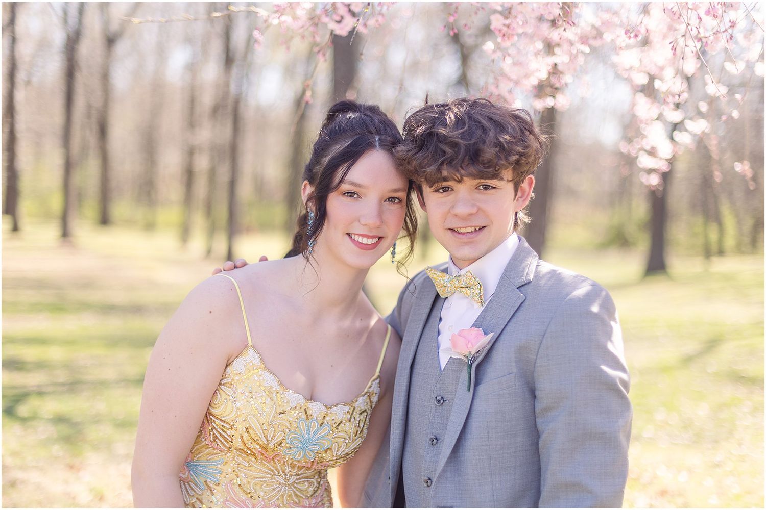 Spring formal portrait under cherry blossoms featuring yellow and gray attire.