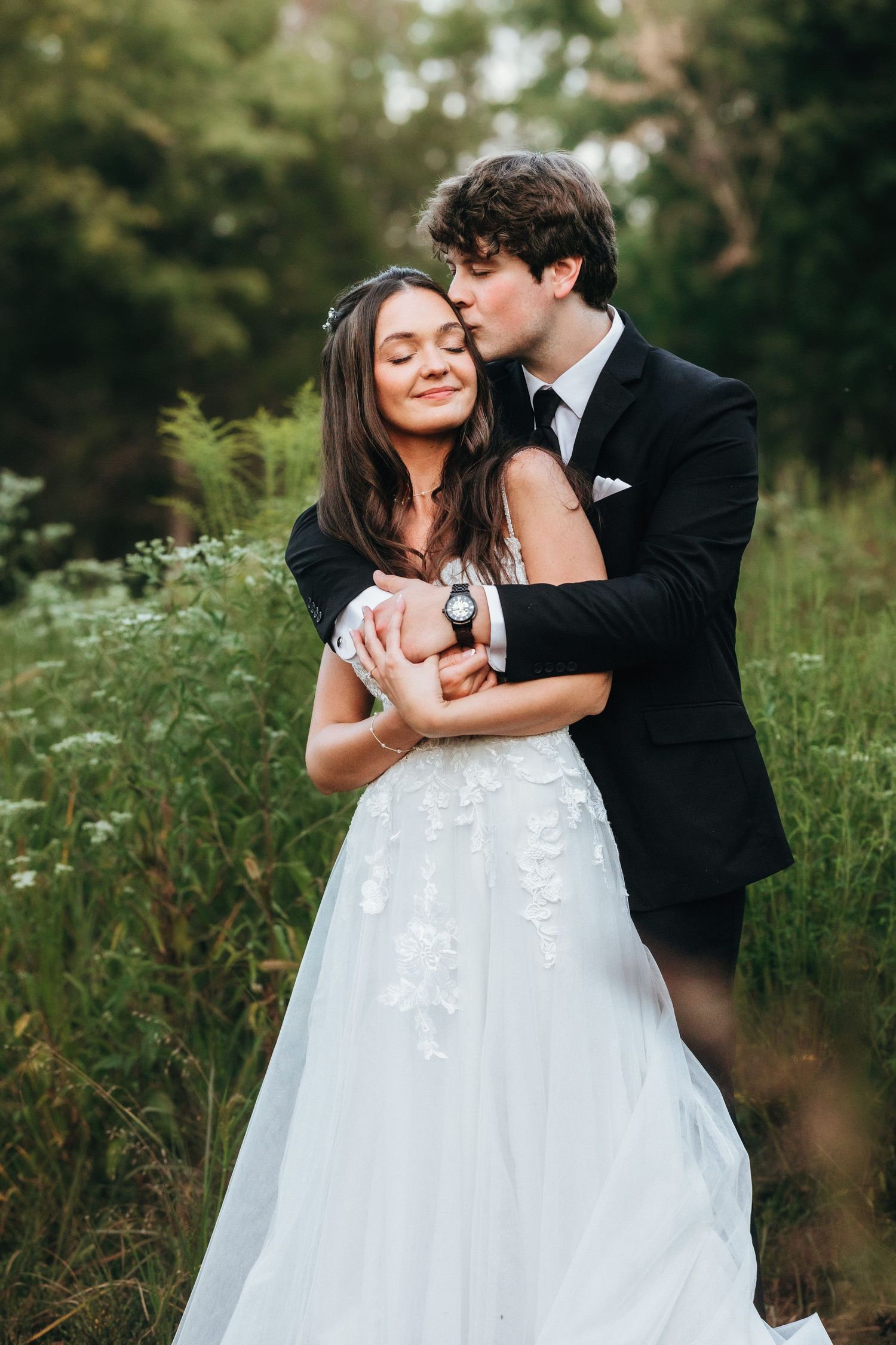 A romantic portrait of newlyweds embracing in a wildflower meadow.