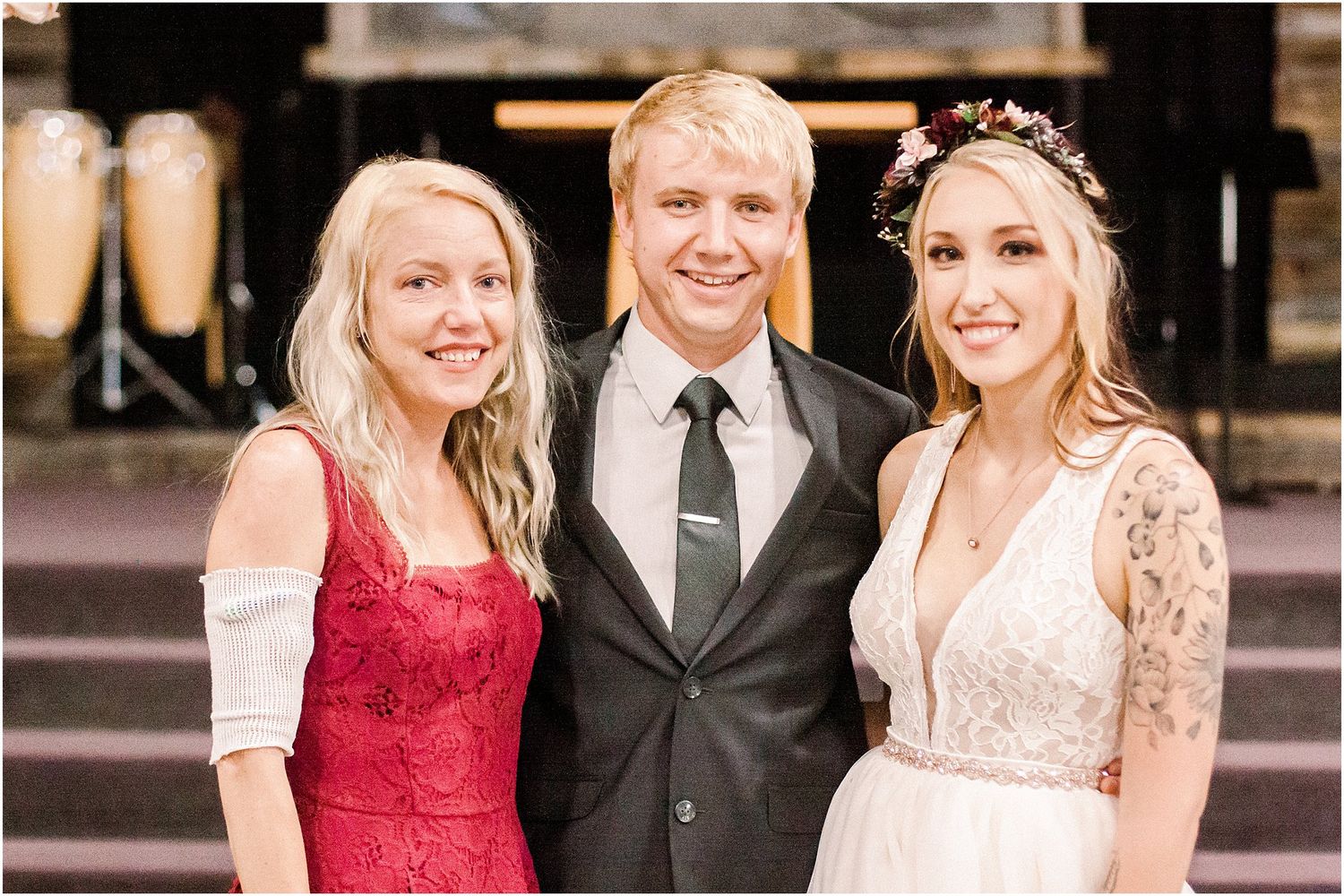 A formal group photo of three people at an outdoor wedding venue.