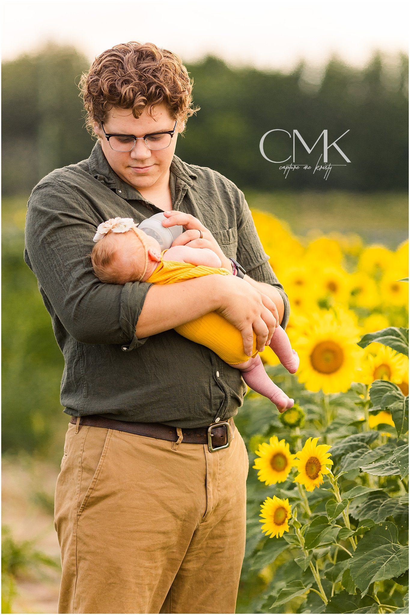 A gentle portrait of parent and baby surrounded by blooming sunflowers.