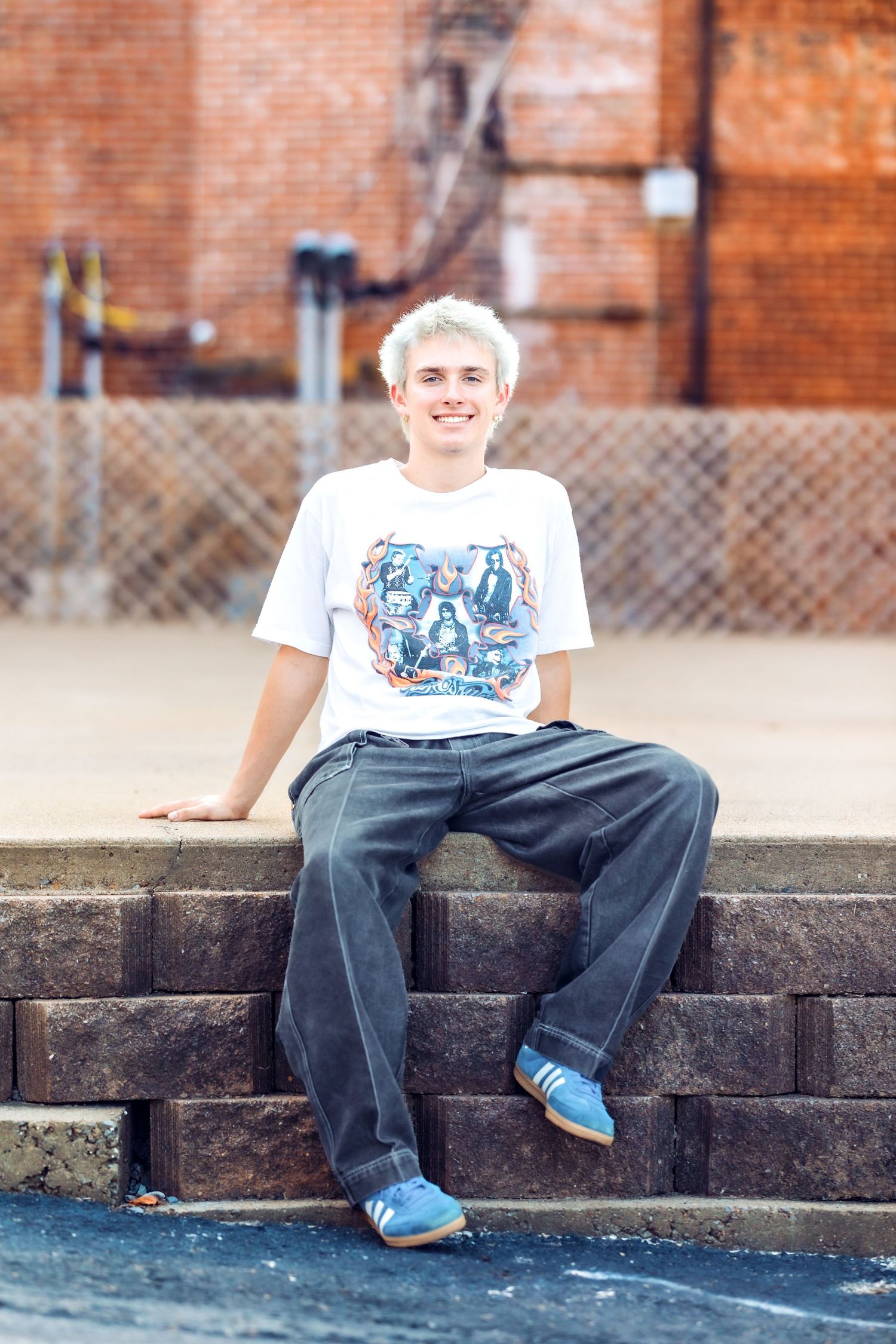 Person in casual attire sits relaxed on concrete ledge wearing blue shoes.