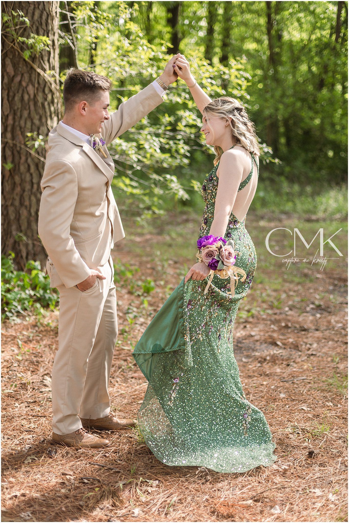 Couple in formal attire dancing in a forest setting with green sparkly dress flowing.