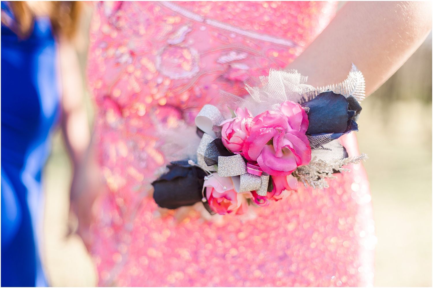 Close-up of pink and blue corsage with roses worn with formal dress.