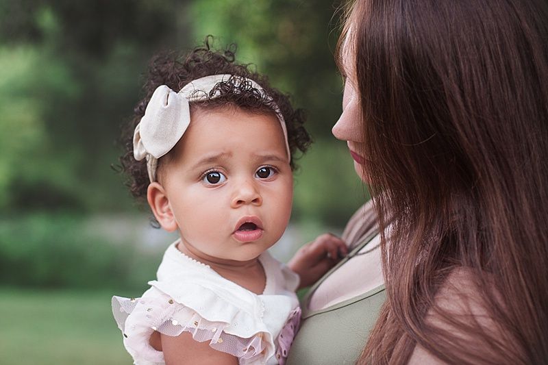 Tender moment captured between parent and child against lush garden background.