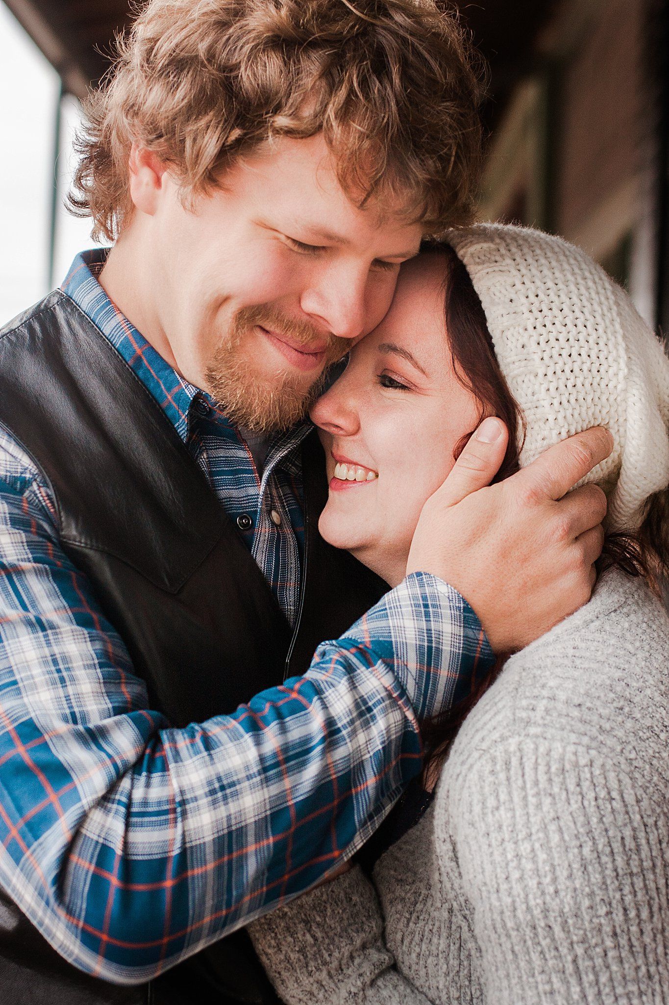 Woman leans on chest of man while he cups her cheek in his hand