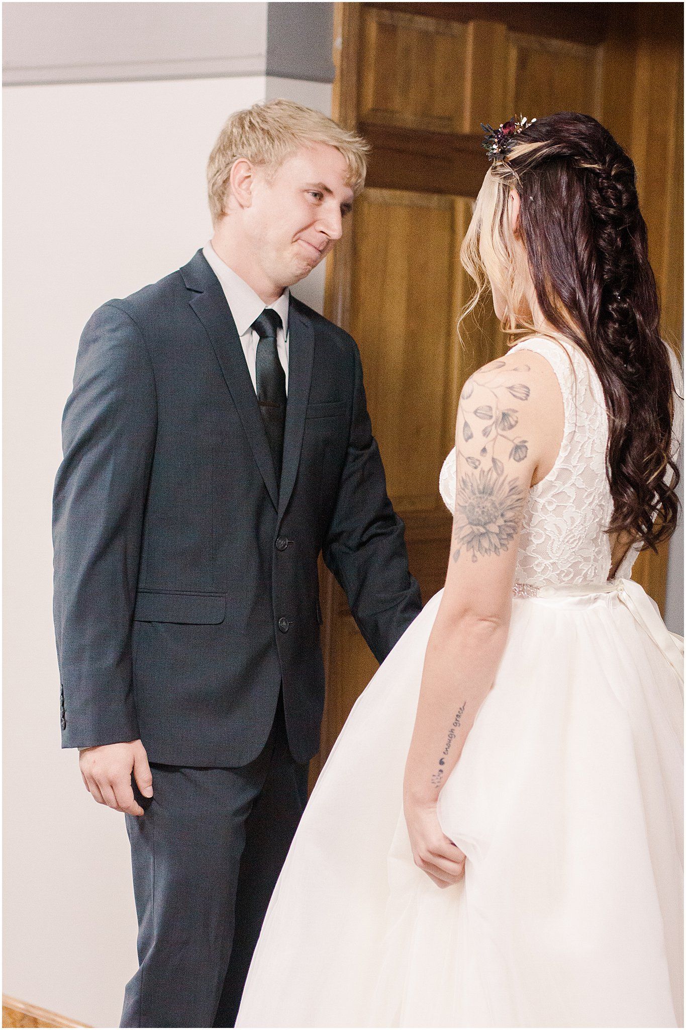 Emotional interaction between newlyweds showing the bride's delicate lace dress and groom's dark suit.