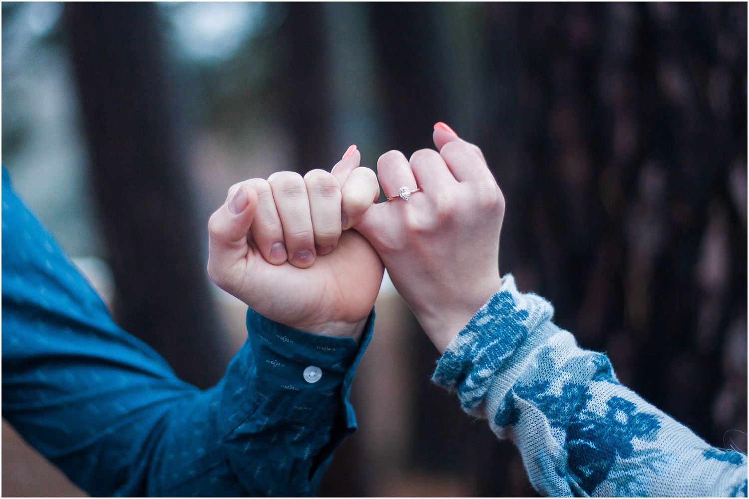 Close-up of two hands linking pinkies in a promise gesture against a dark background.