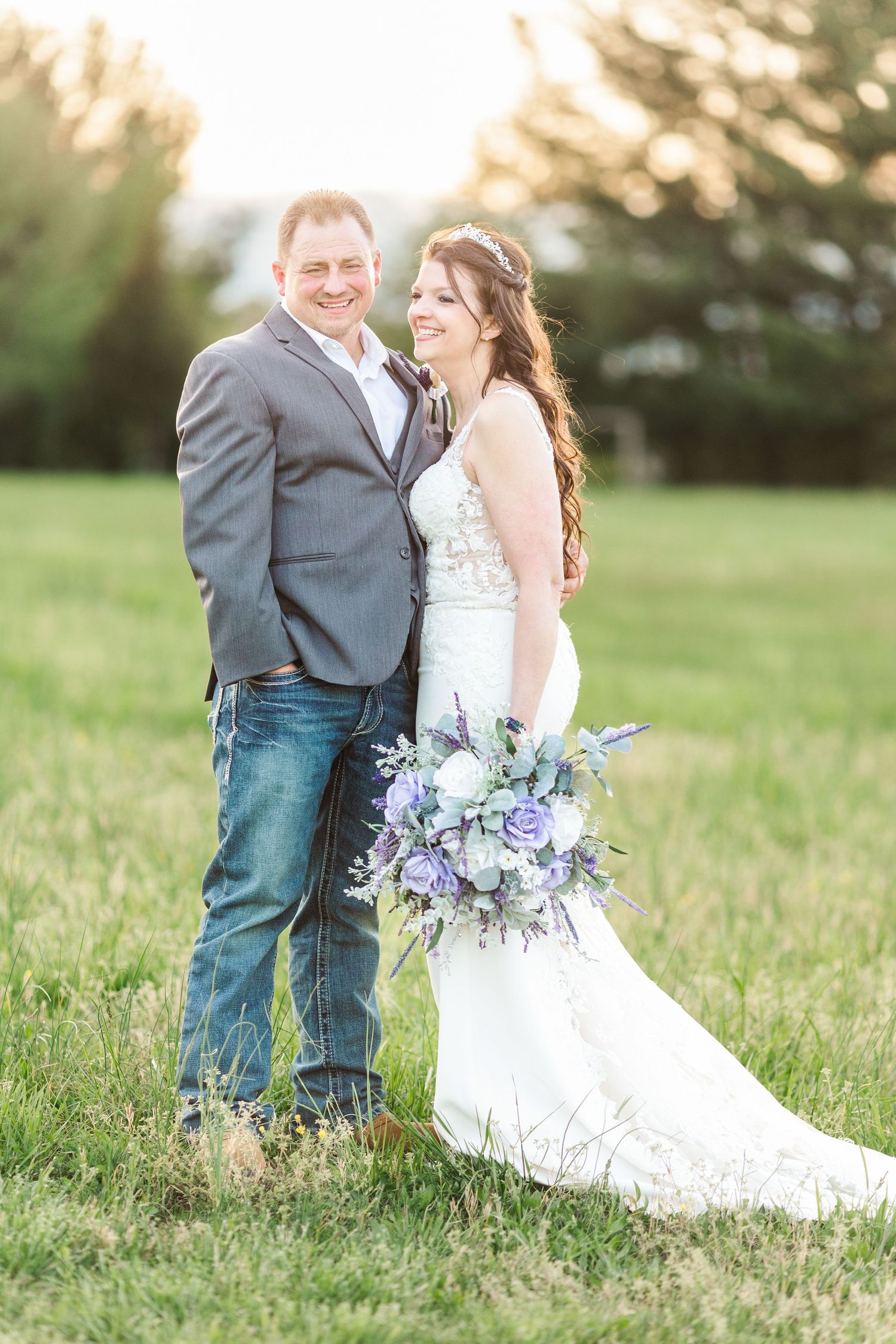 Couple shares intimate moment in grassy field during sunset wedding photos.
