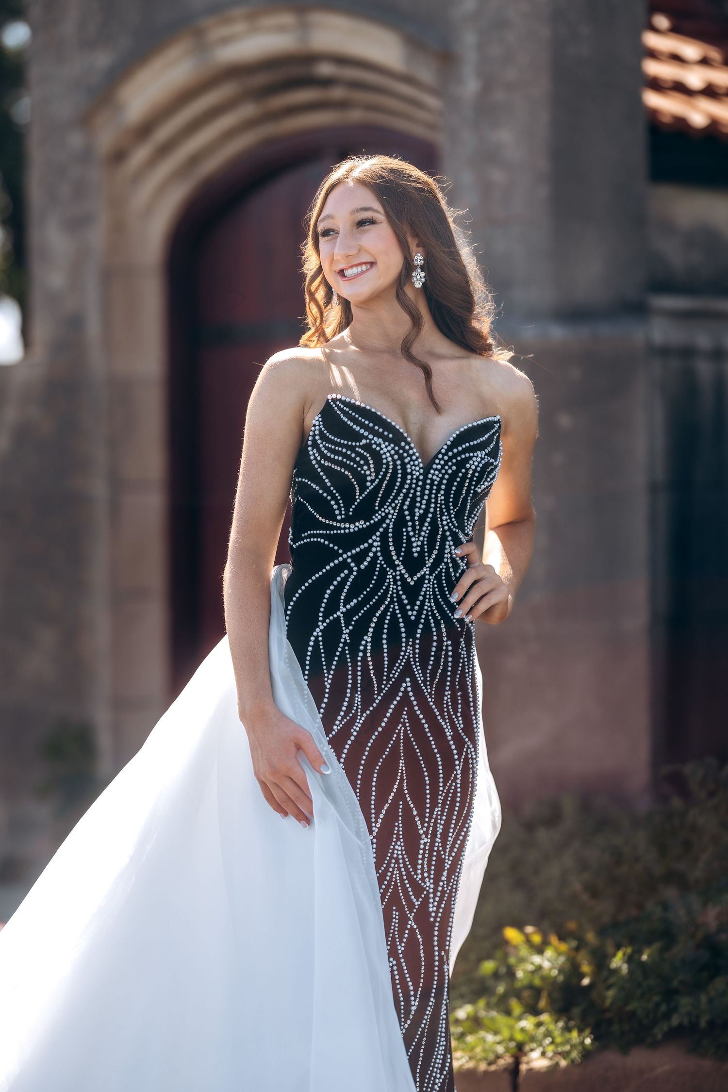 A stunning black sequined gown with white tulle detailing photographed in an elegant outdoor setting.
