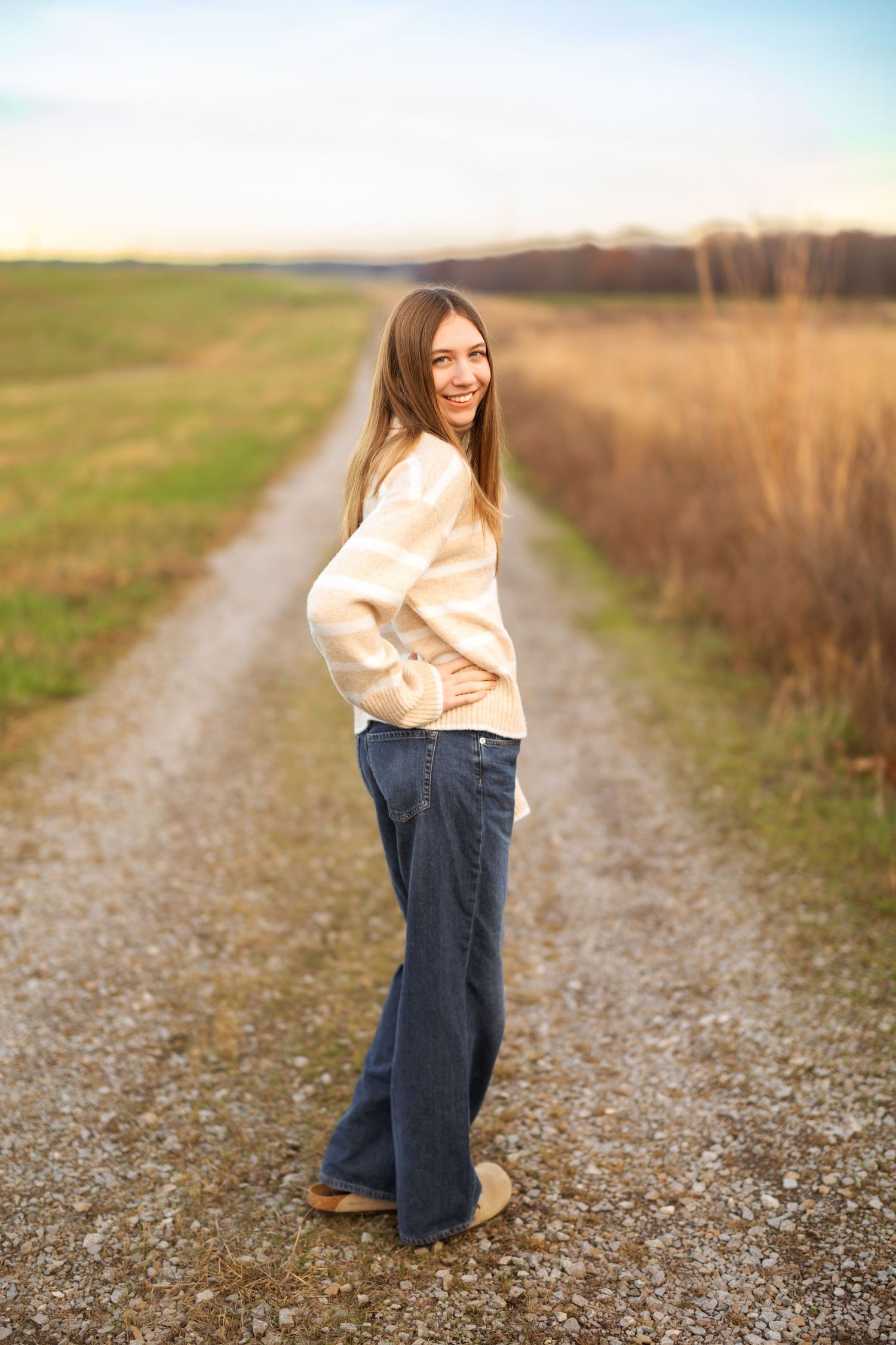 Person in casual outfit strolling down rural gravel road.