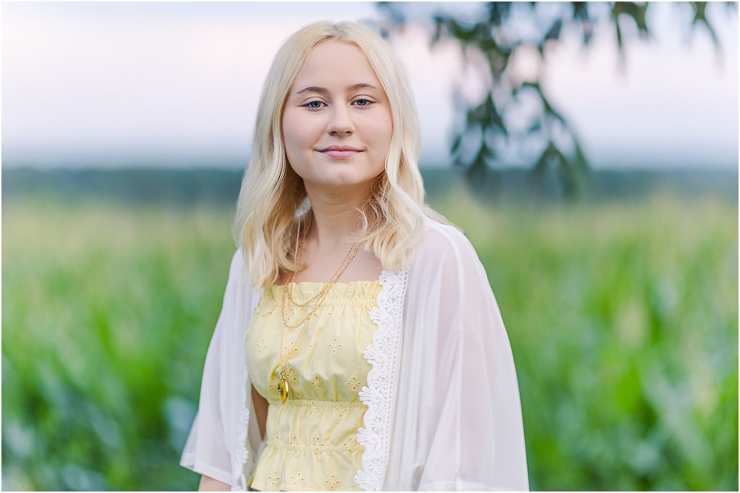 Senior girl in front of a corn field at sunset