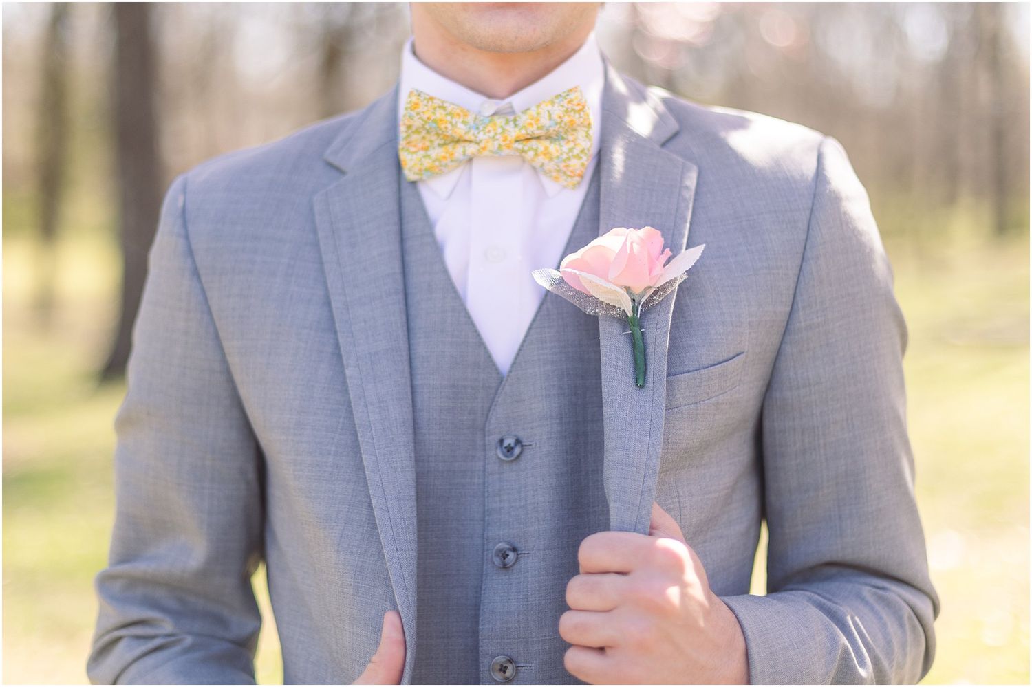Close up of gray suit with yellow bowtie and pink boutonniere detail.