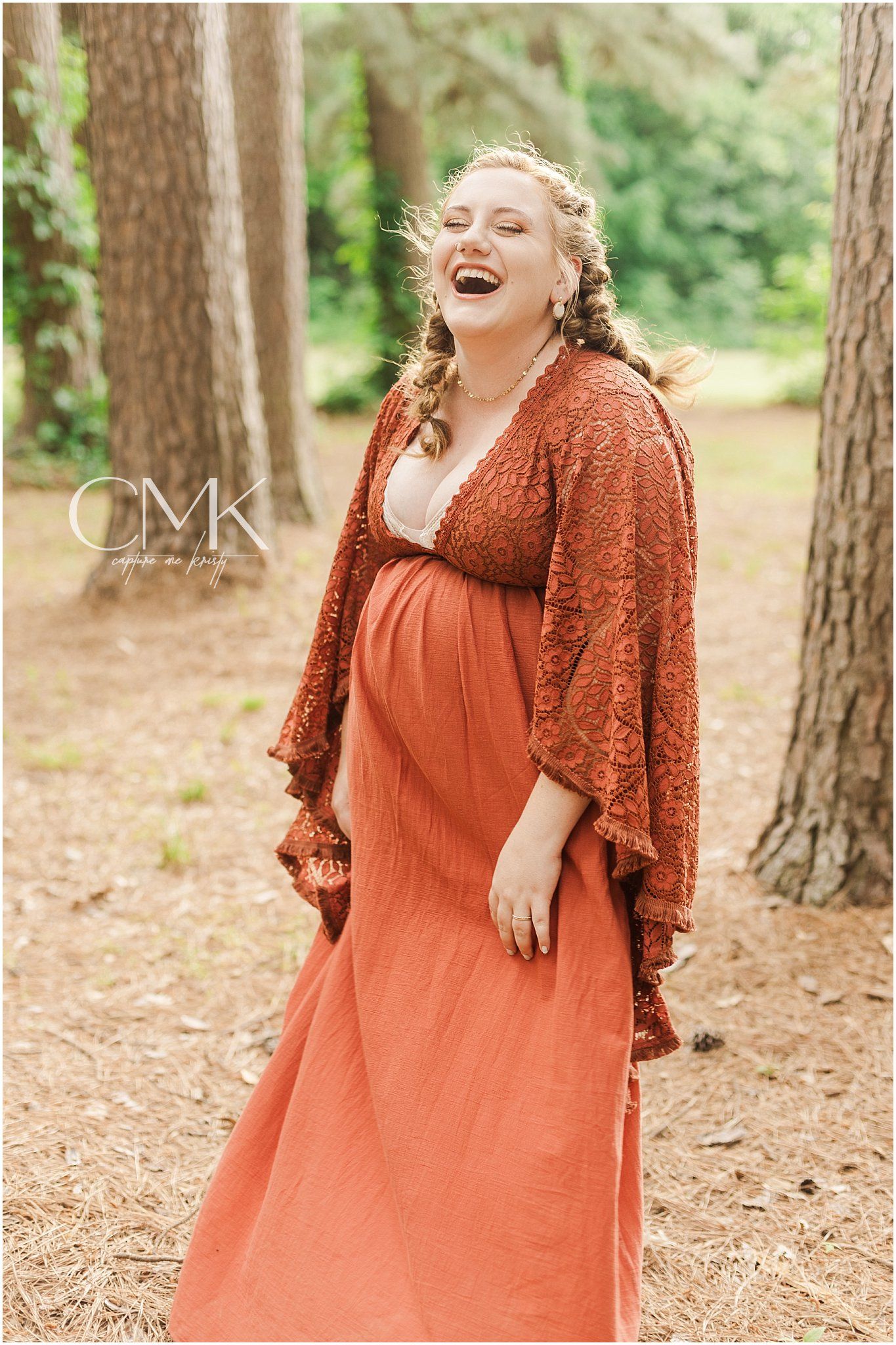 Joyful maternity portrait captured in a wooded setting with natural lighting.