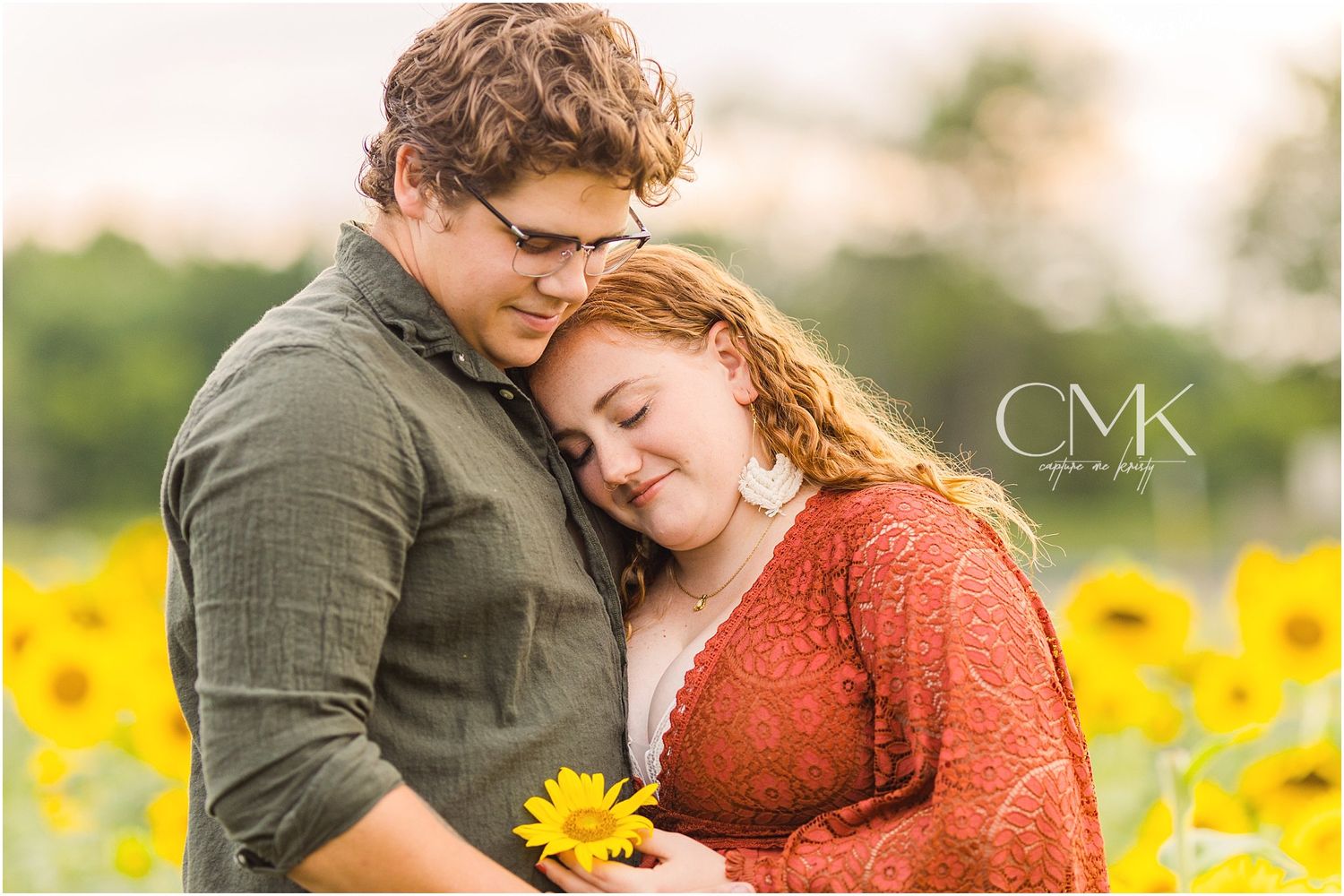 An intimate moment photographed in a sunflower field during golden hour.