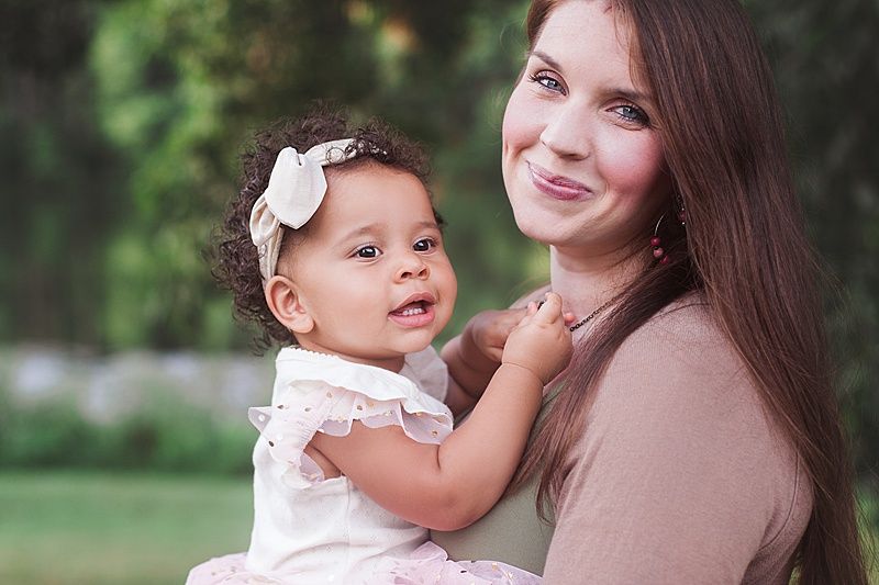 Natural lifestyle portrait of parent and child smiling together in garden setting.