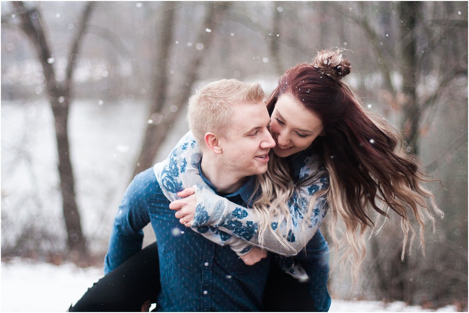 A romantic winter photoshoot captures a playful piggyback ride moment in the snow.