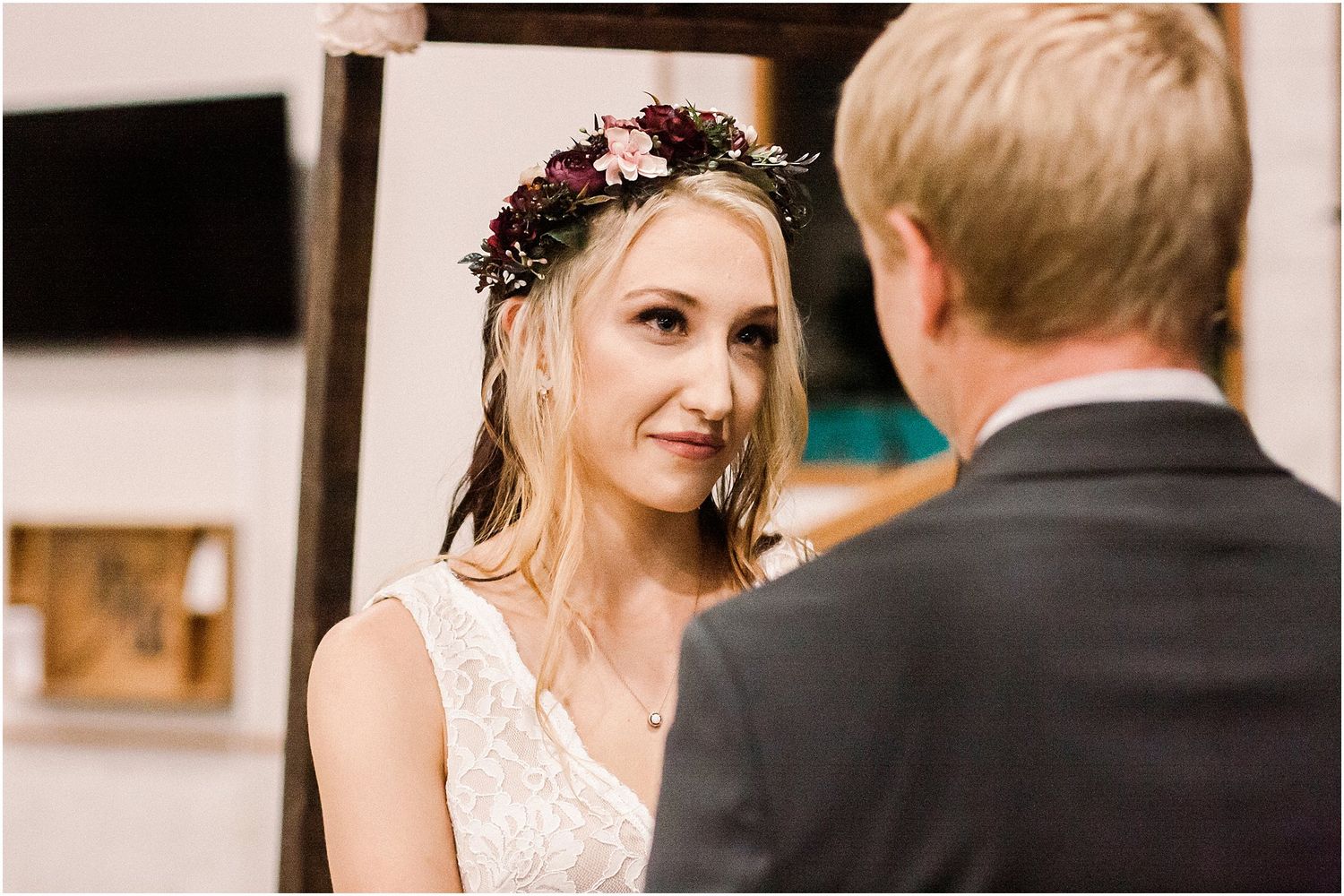 Side profile of bride wearing floral crown and lace dress during ceremony.