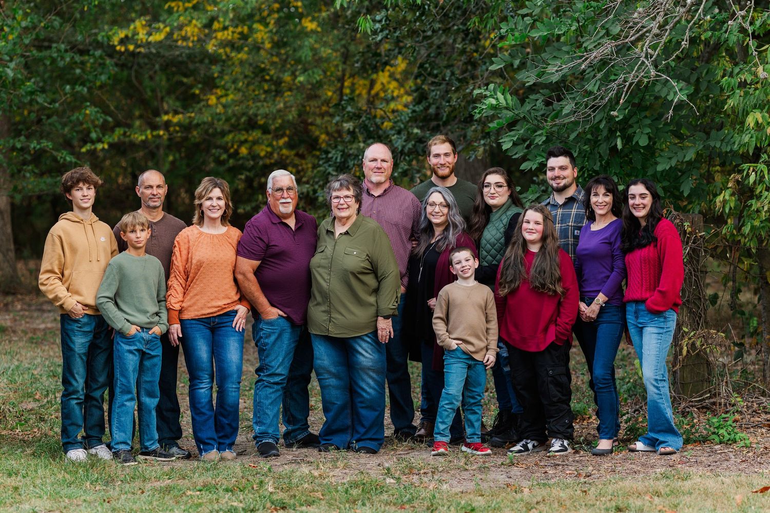 Large extended family group photo session with multiple generations in outdoor fall setting.